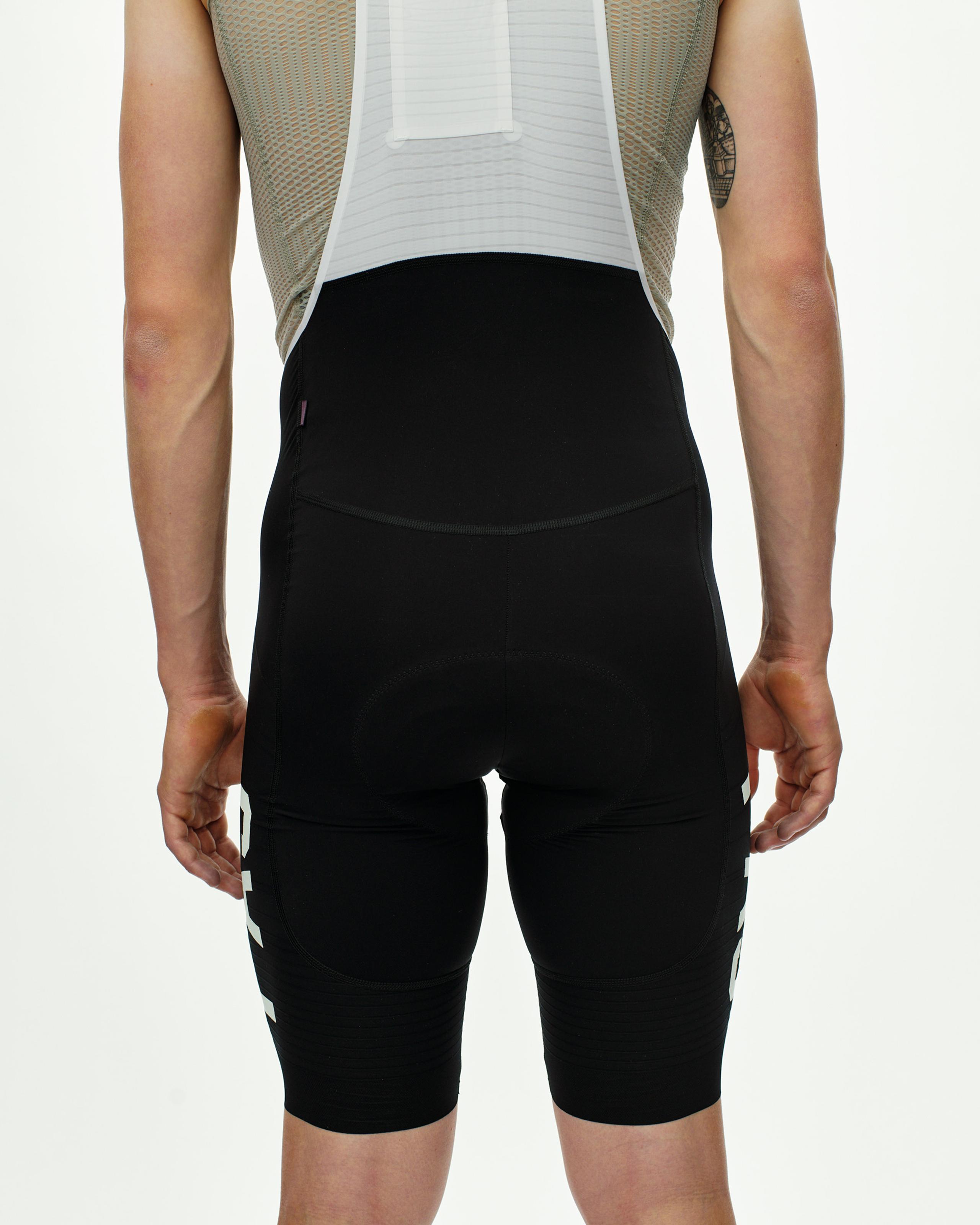 Black PAS Mechanism Pro cycling bibs, rear view on model with high waistband