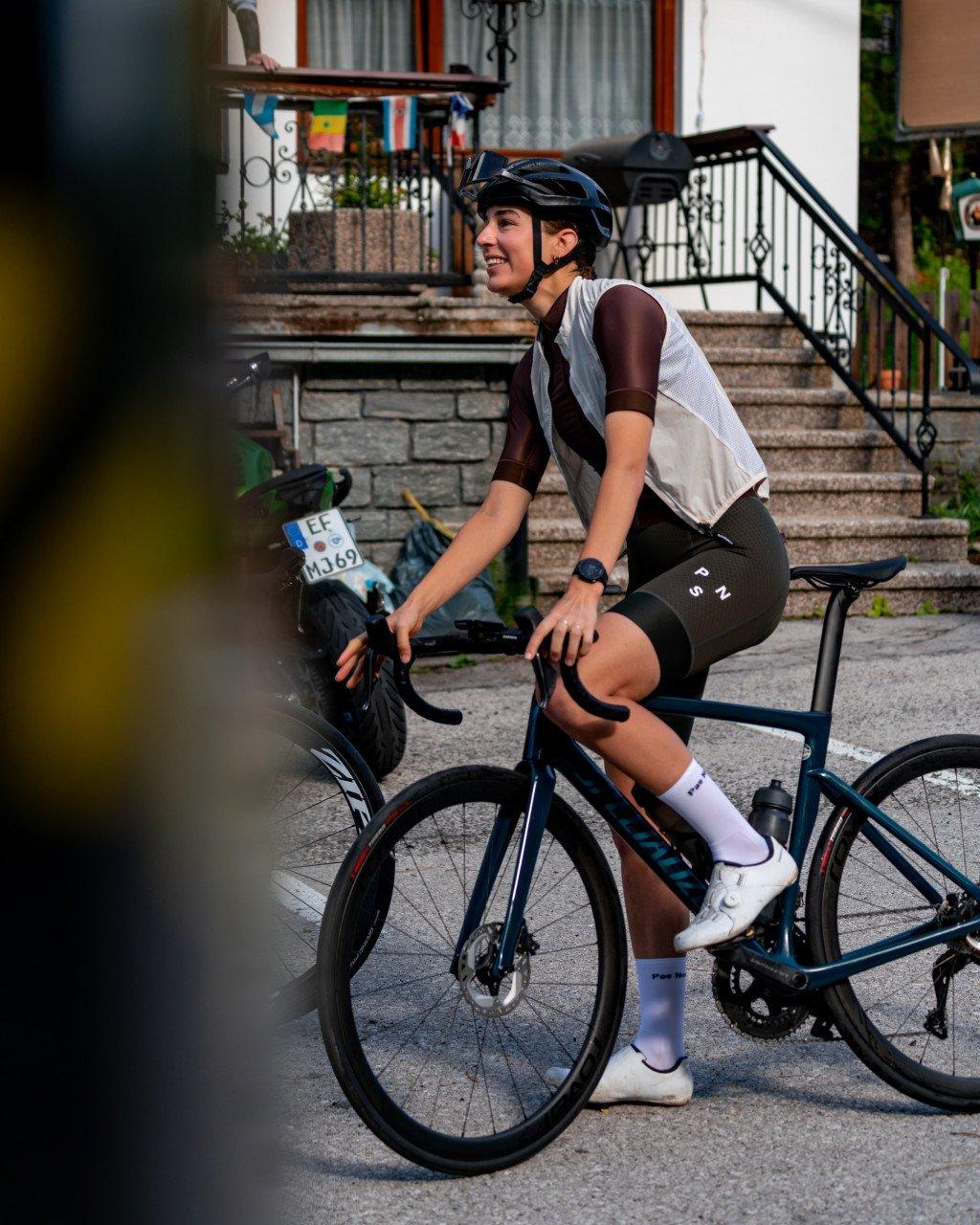 Model wearing white mesh jersey and black shorts on time trial bike in urban setting