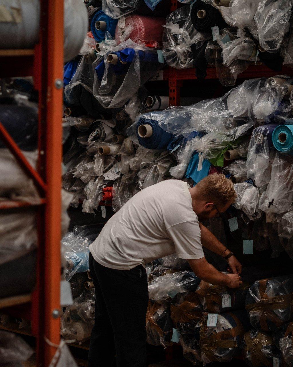 Person sorting through fabric rolls and materials in textile warehouse