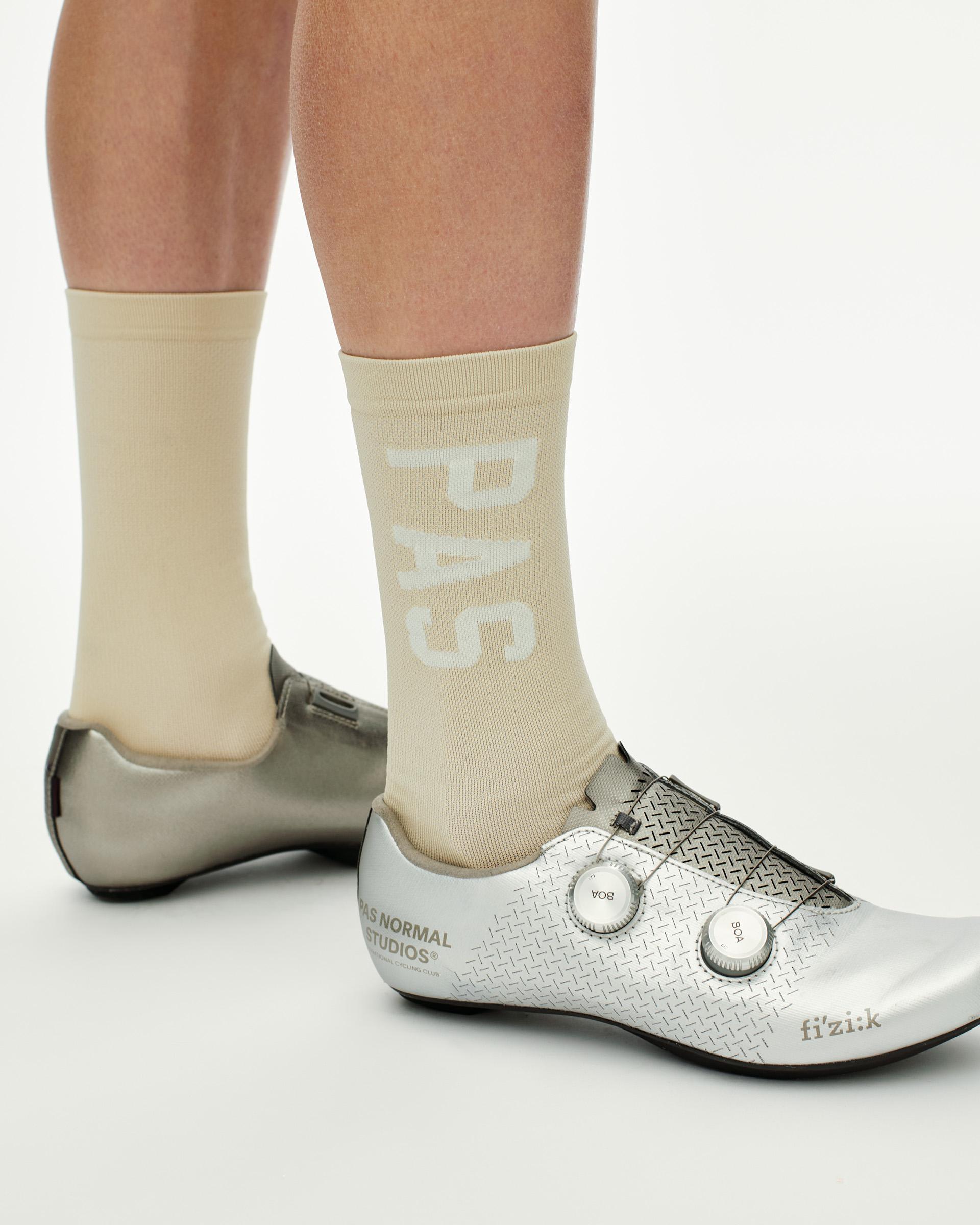 Cream PAS cycling socks on model with white PAS branding