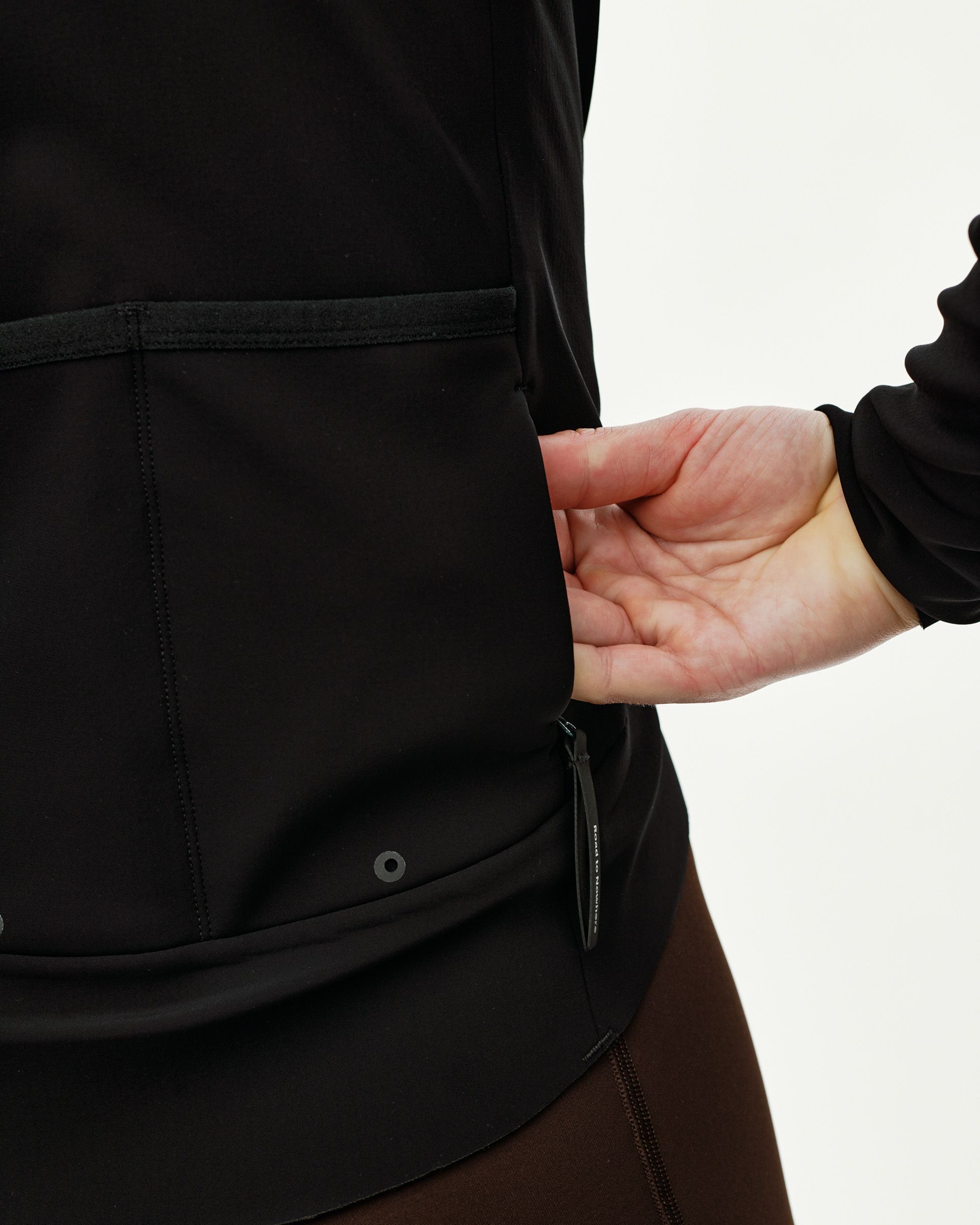 Black Mechanism Thermal cycling jacket, detail view on model showing rear pockets with zip pocket pull