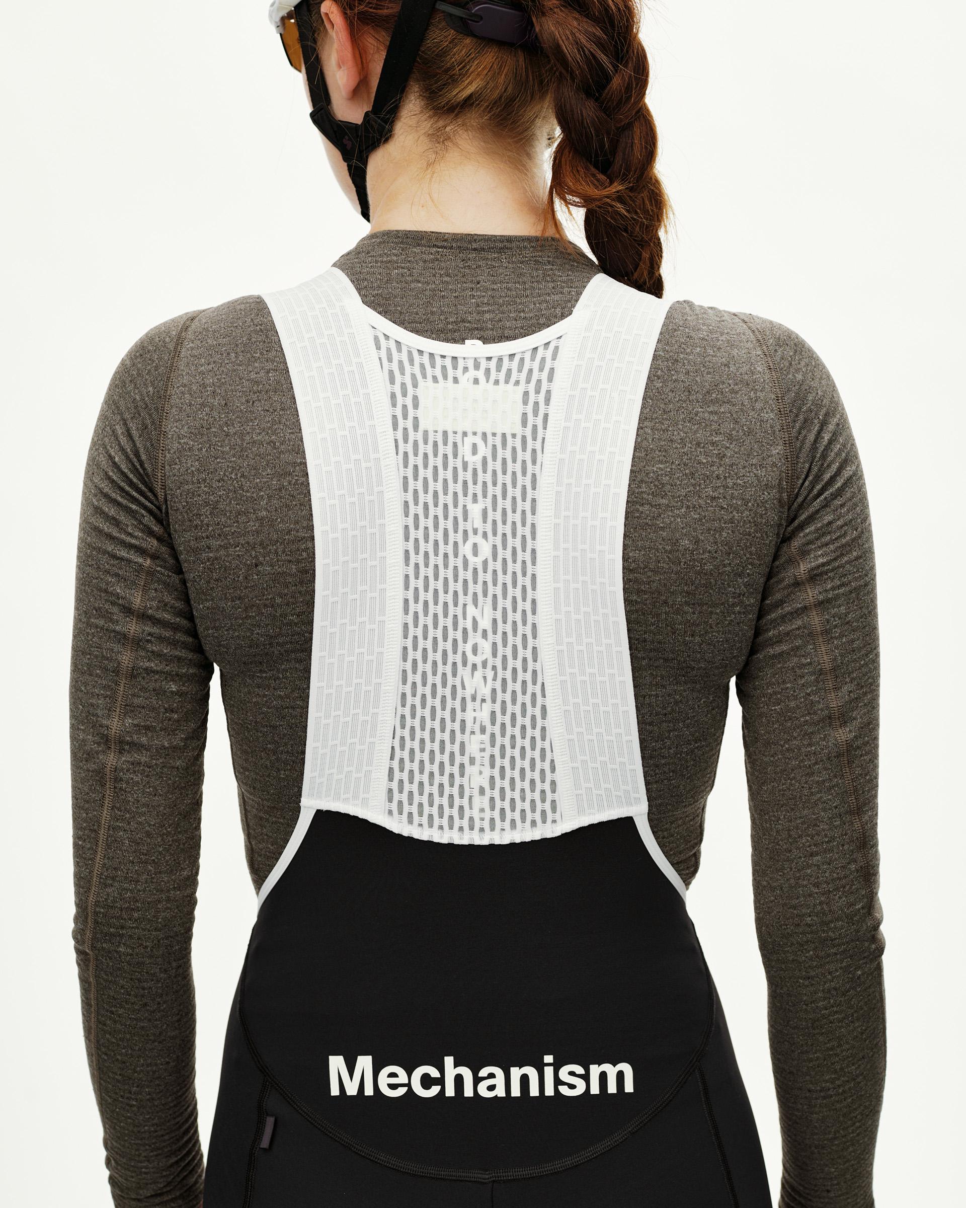 Black Mechanism women's thermal long cycling bibs, rear view on model with white mesh bib straps and logo print