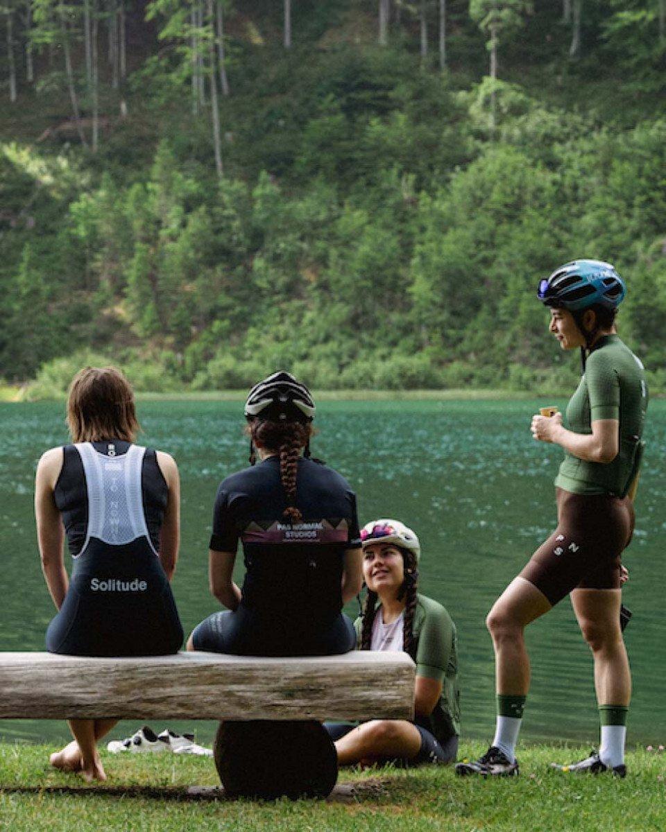 Cyclists resting by lake wearing navy and green cycling apparel