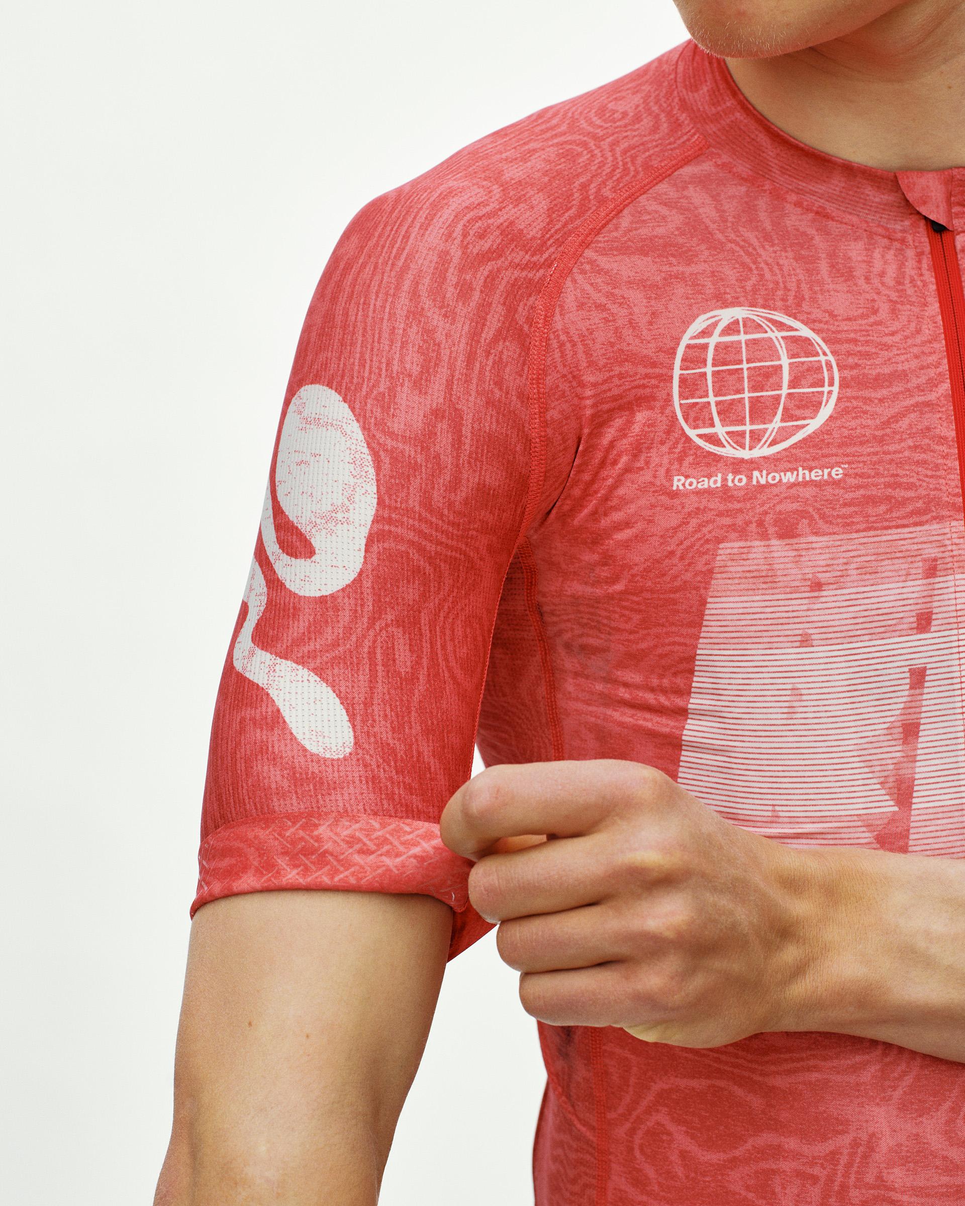 Red Mechanism cycling jersey on model, detail view with Road to Nowhere globe chest print and topographic pattern