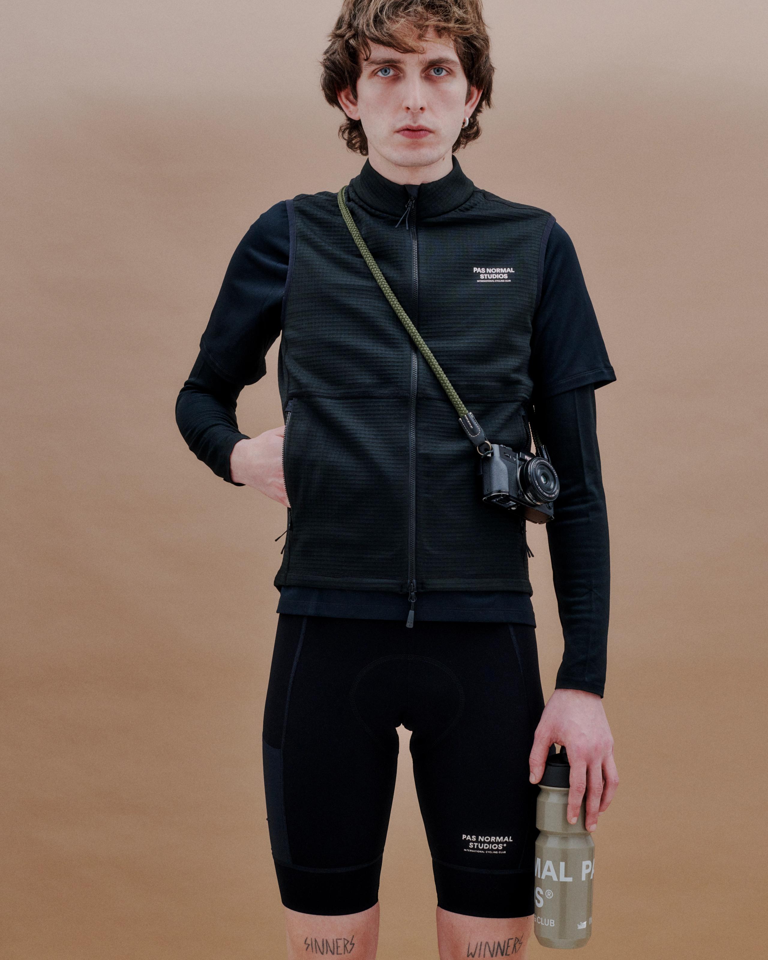 Beige Escapism water bottle held by model in dark cycling kit