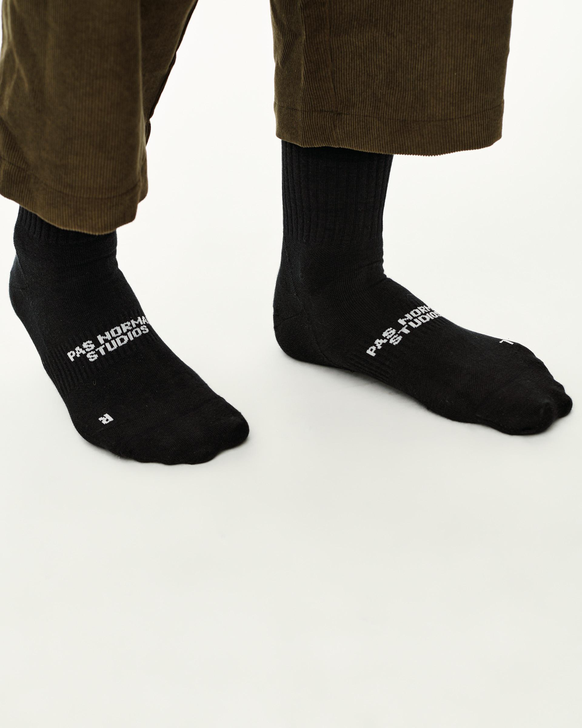 Black Off-Race socks on model, pair showing white logo print on foot and ribbed cuff