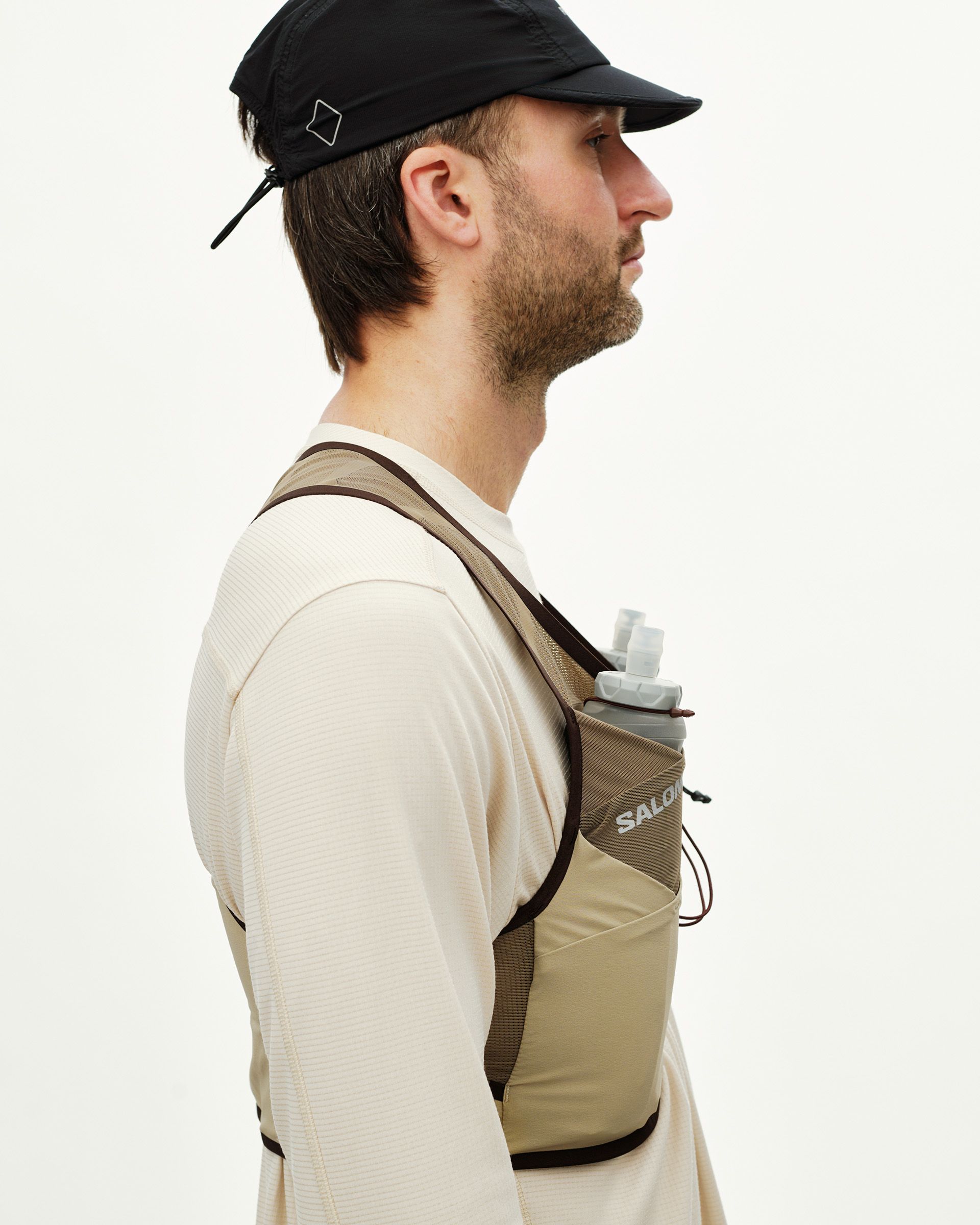Light Brown Salomon Gravel Concept Skin 2 running vest on model, side view with chest bottle holder