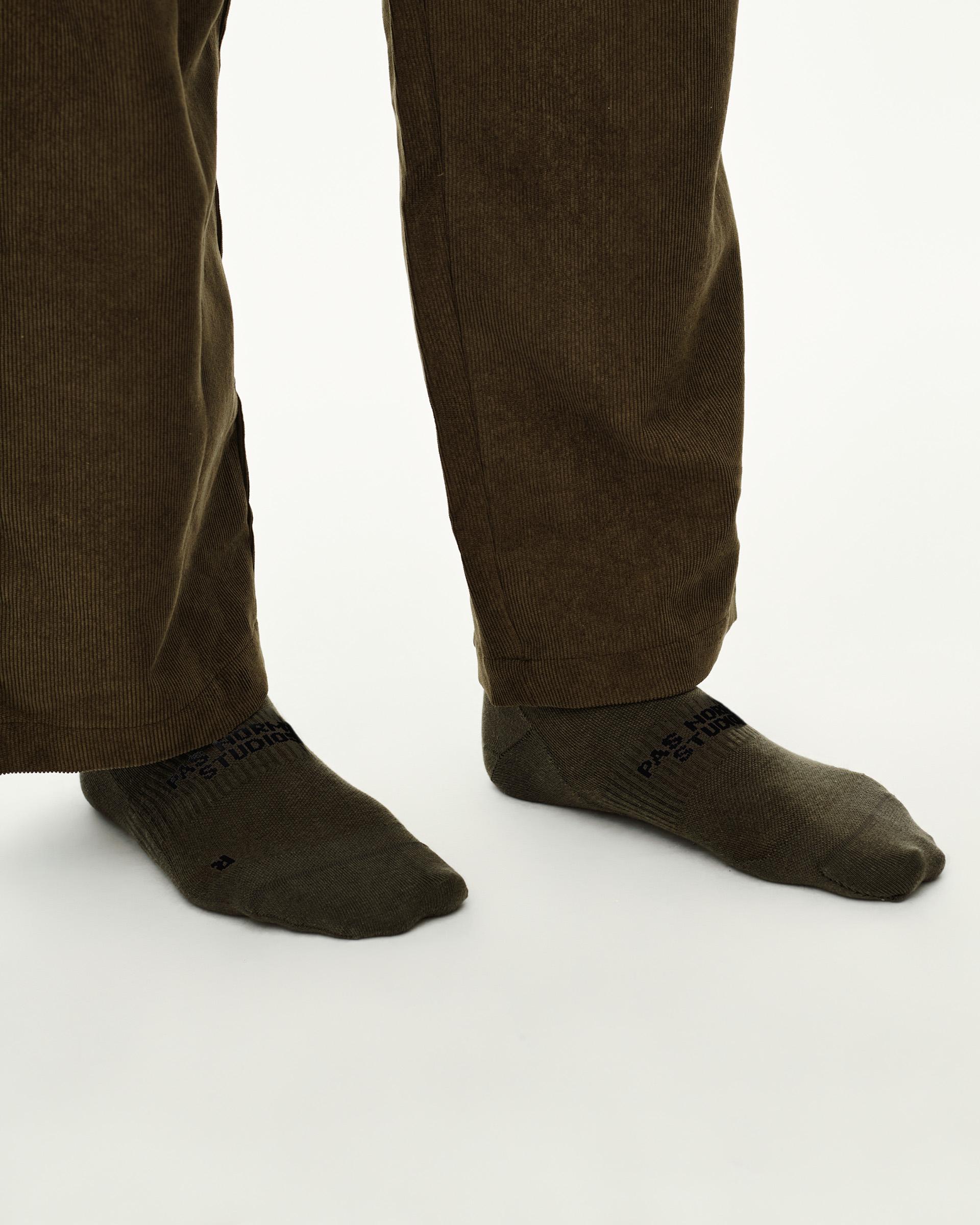 Grey Green Off-Race socks on model, side view pair with black logo text at ankle