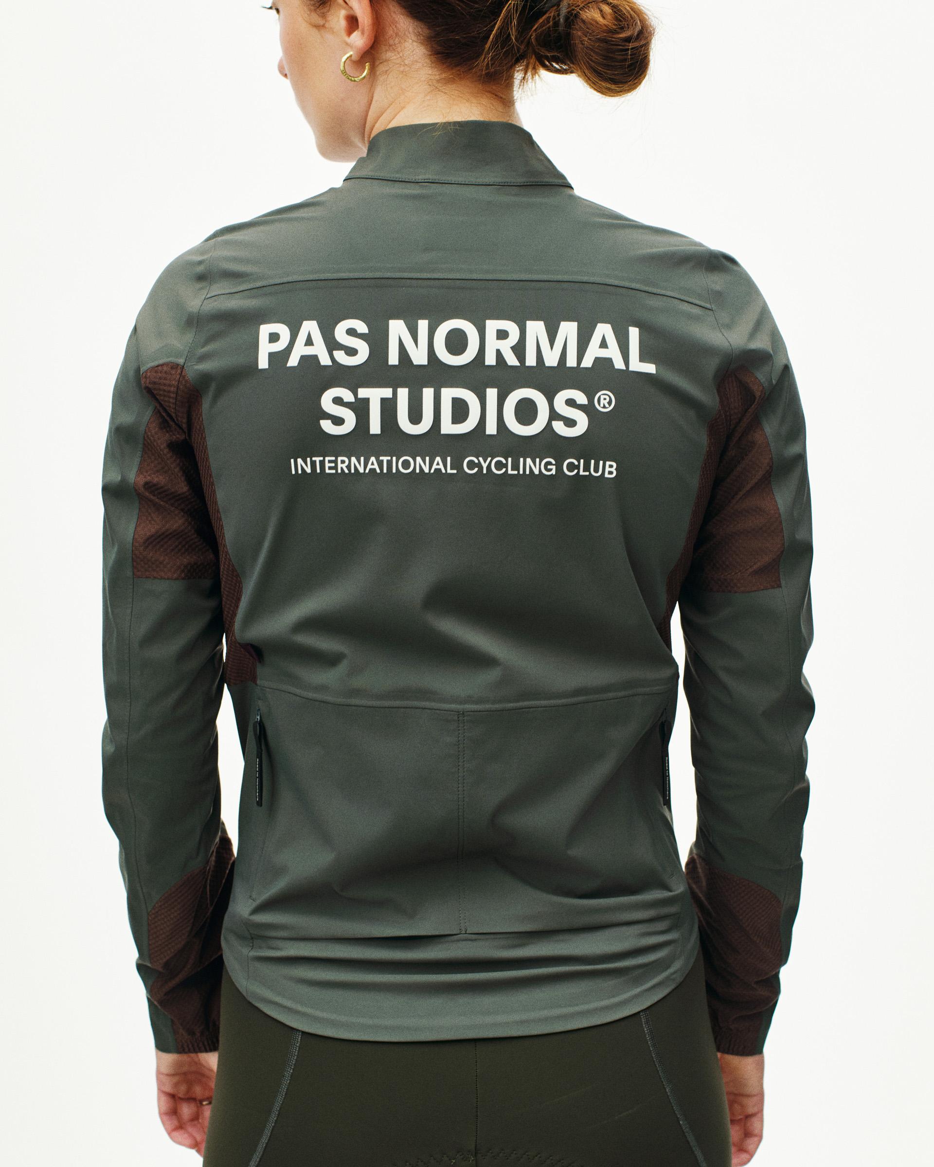 Dark Grey Mechanism Shell cycling jacket on model, rear view with white back logo and mesh side panels