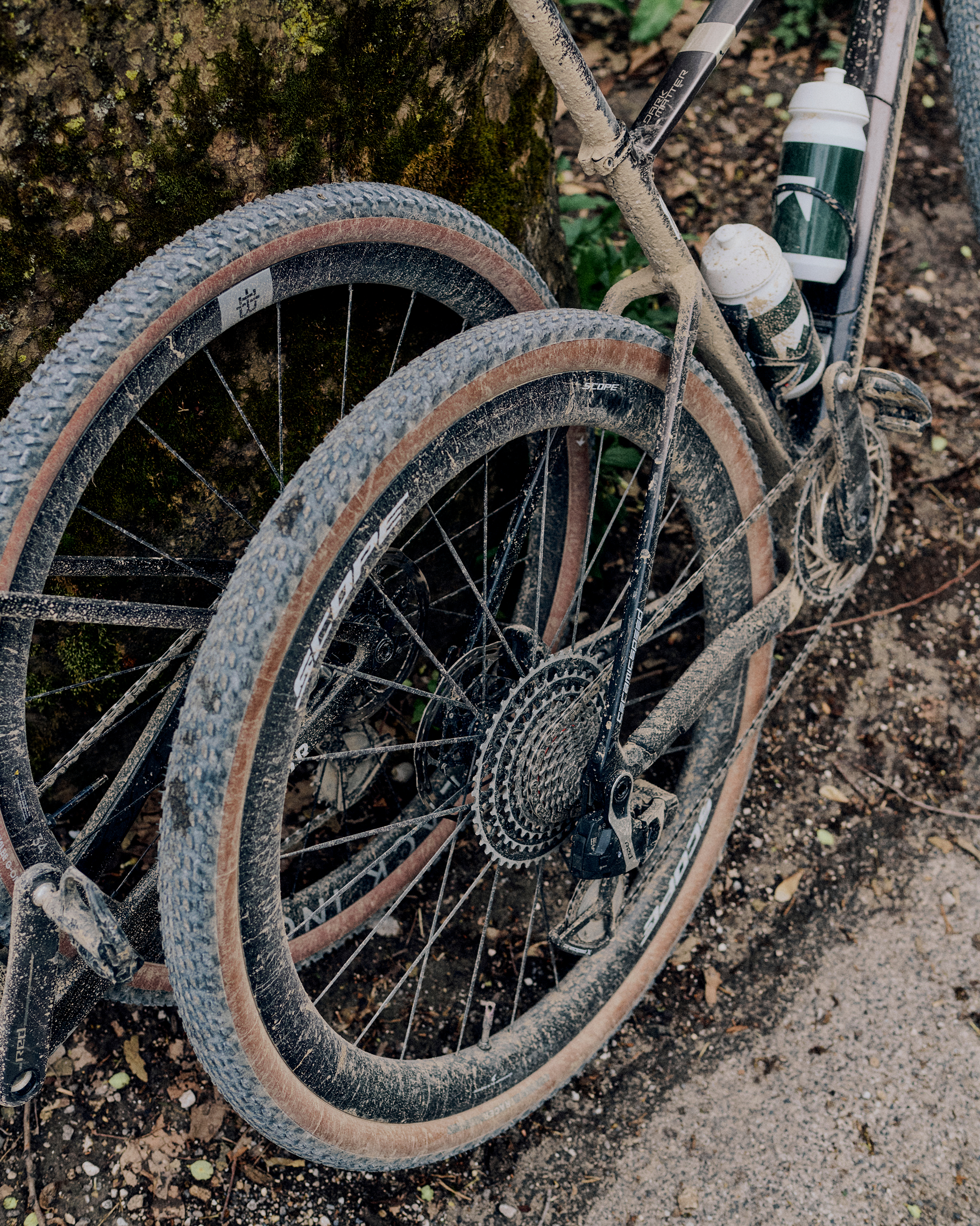 Gravel bike wheels covered in mud and dirt on trail surface