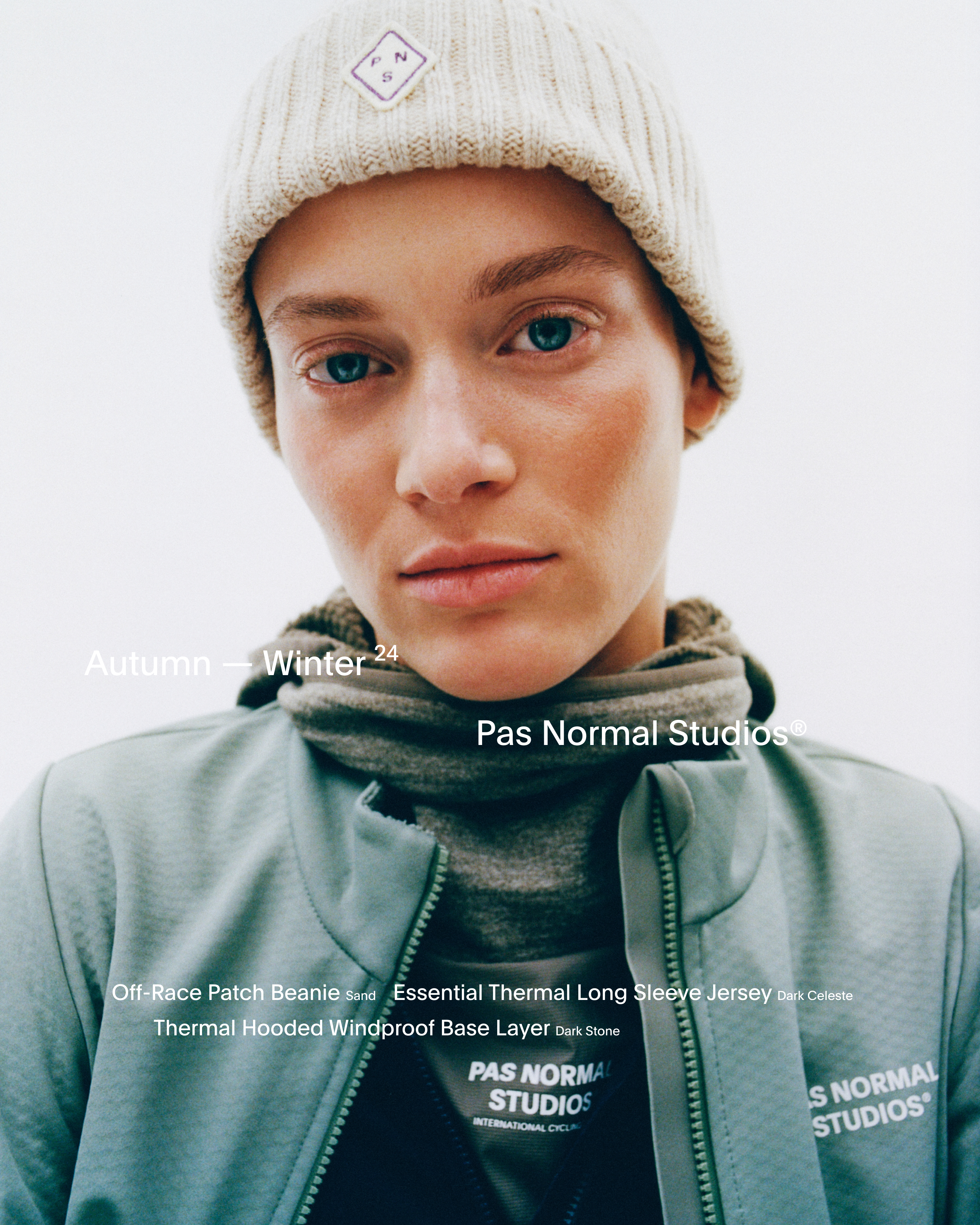 Model wearing cream Off-Race Patch Beanie, dark thermal jersey, and light green windproof base layer