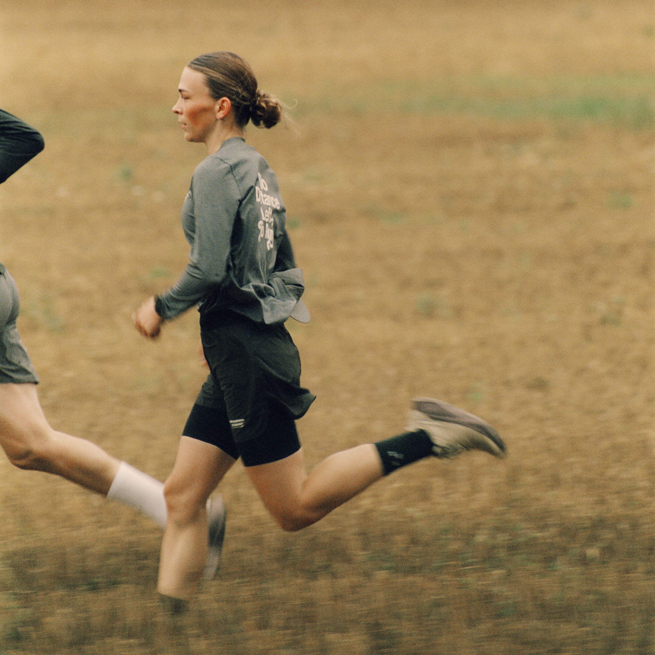Model wearing green running jacket with back graphics and black shorts running outdoors