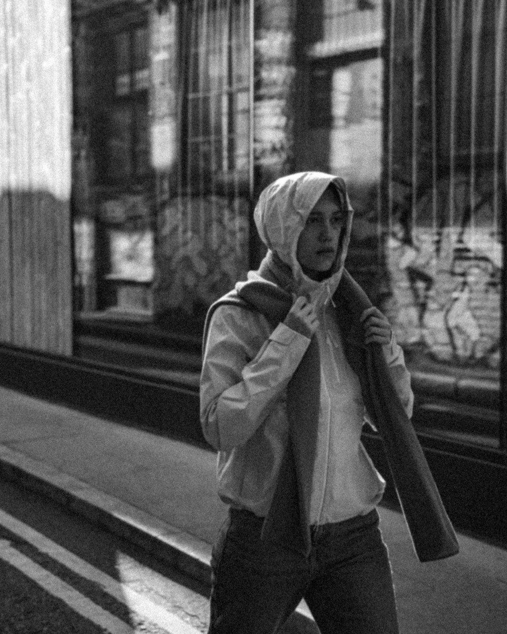 Model wearing hooded jacket on urban street, black and white photo