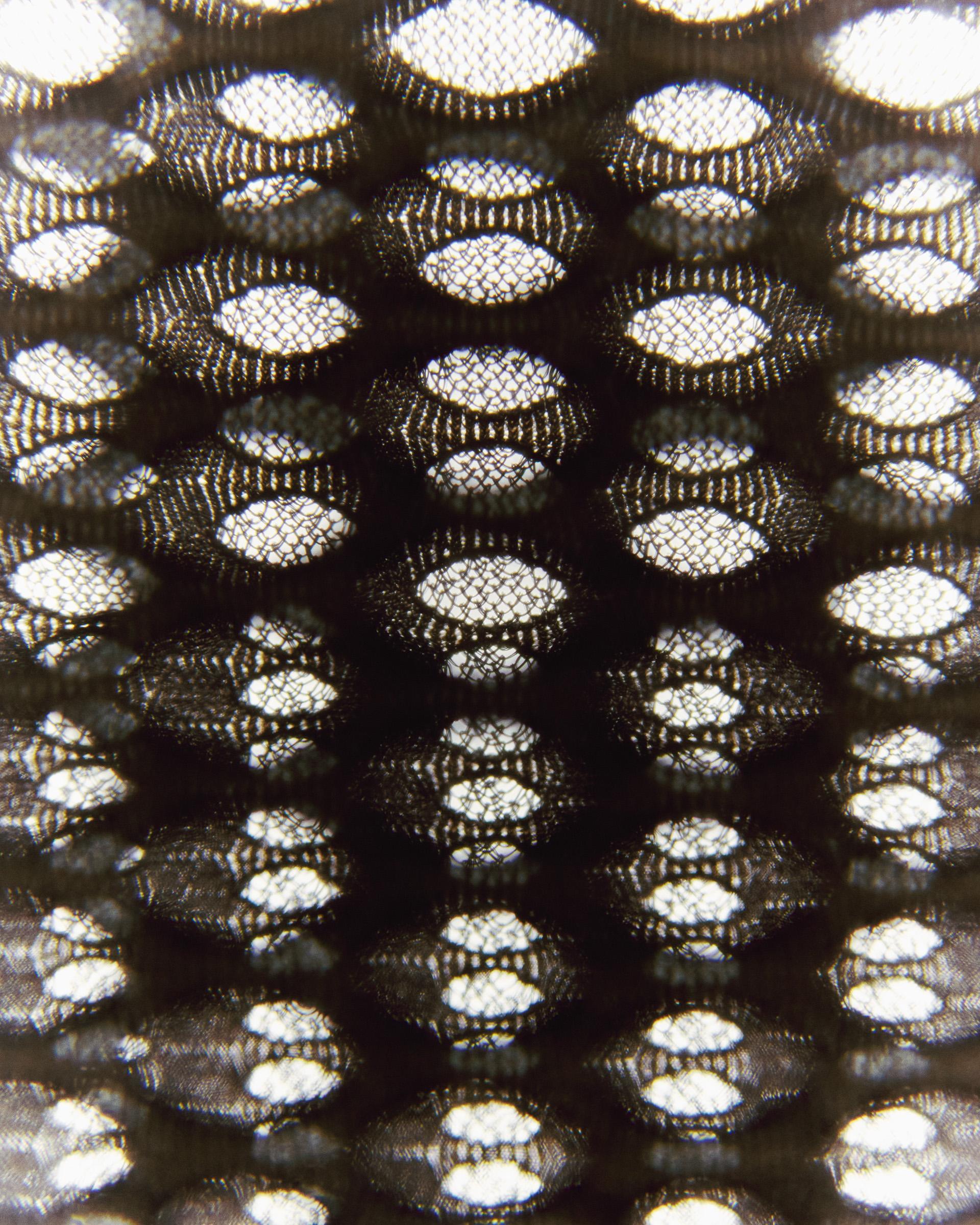 Close-up of black mesh fabric with hexagonal perforations showing ventilation pattern