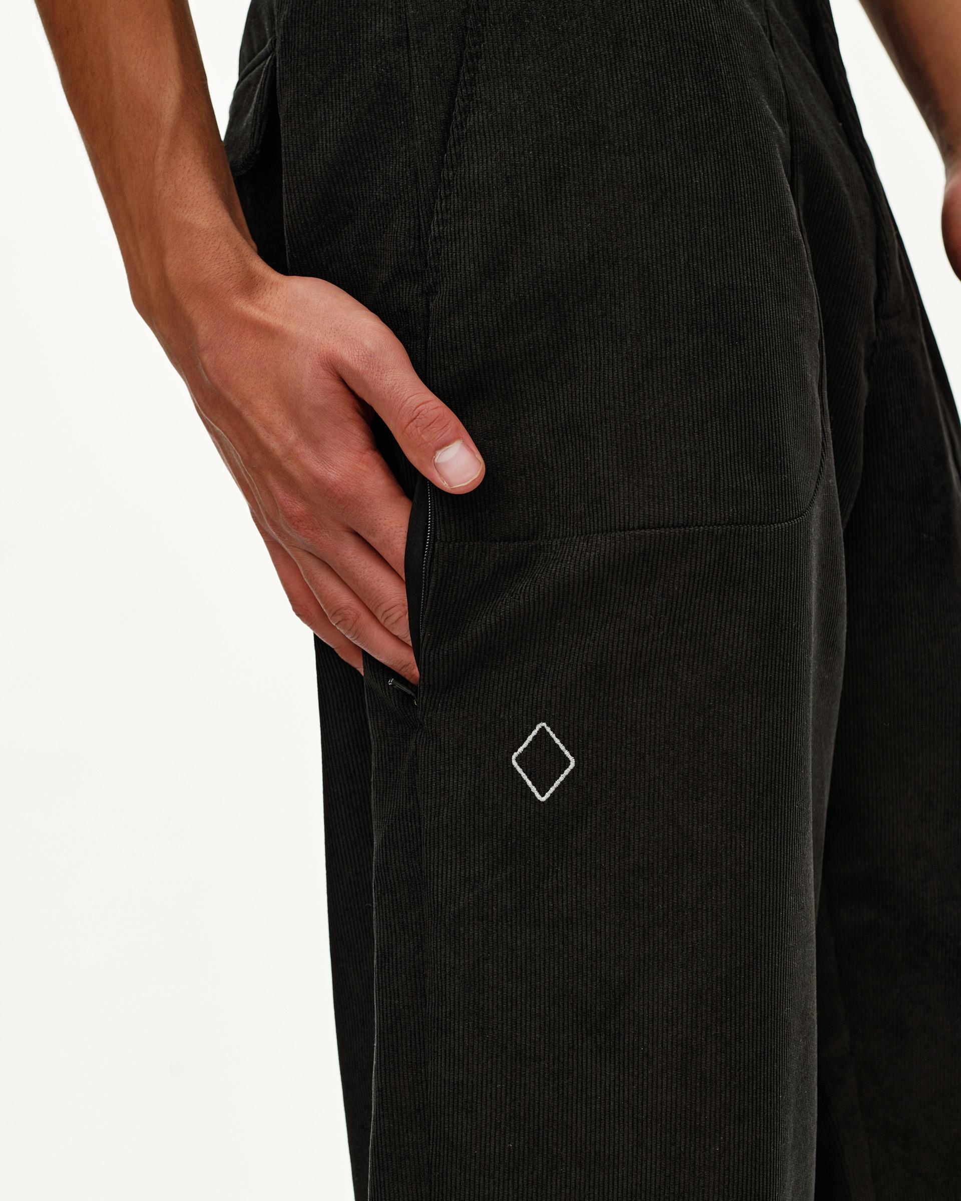 Black Off-Race Corduroy pants, side detail on model showing zip pocket and diamond logo embroidery