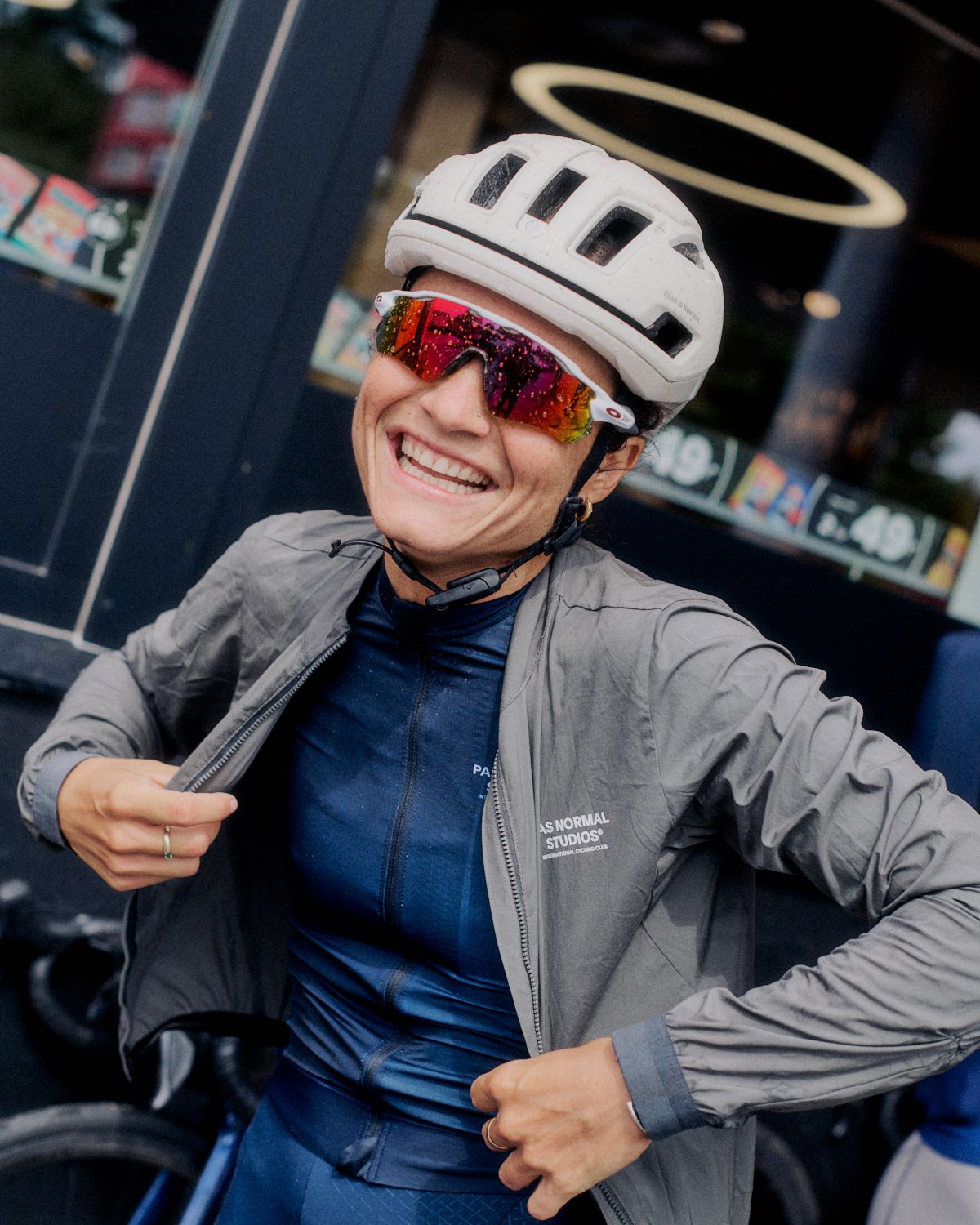 Model wearing blue base layer and grey jacket with helmet and sunglasses at cycling event