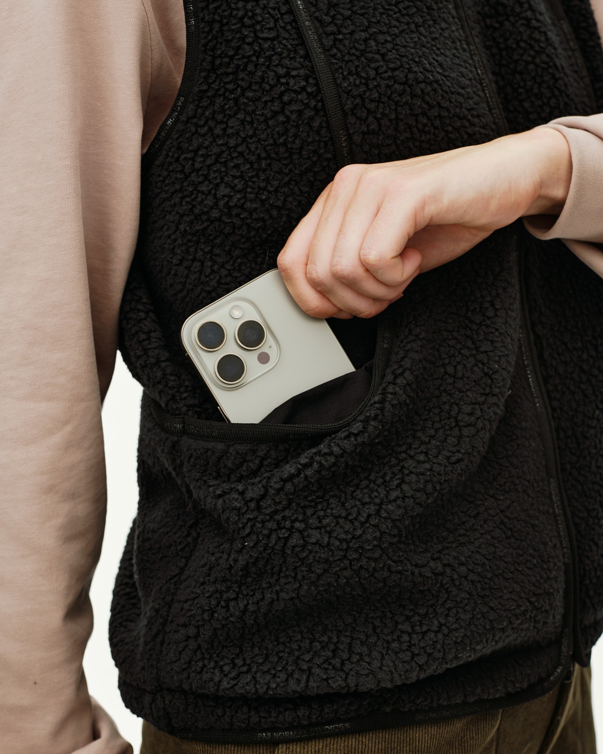 Black Off-Race Pile Fleece Vest, detail view of hand placing phone into zip pocket