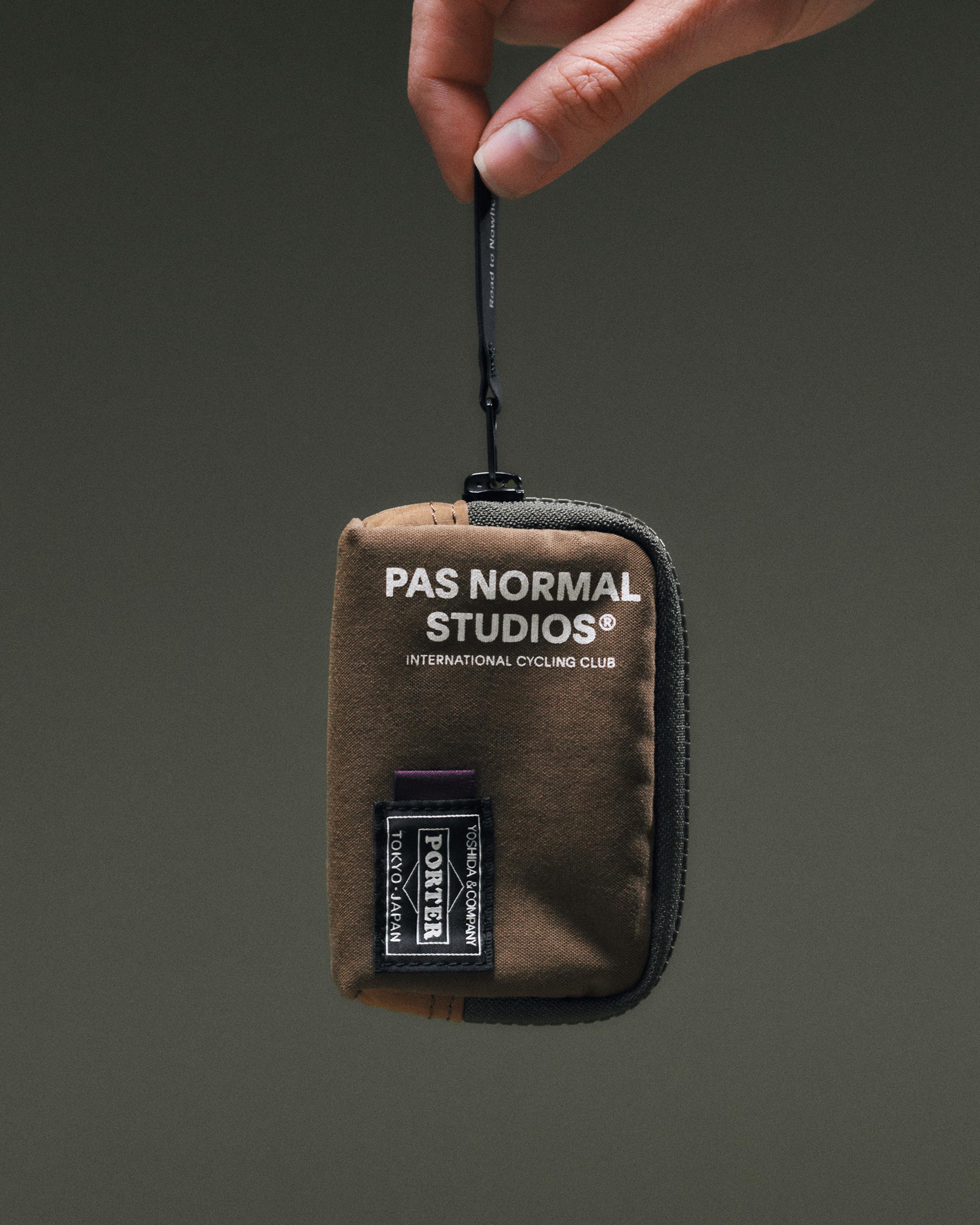 Light Brown Porter-Yoshida coin case held by hand, front view with white logo print and Porter woven patch
