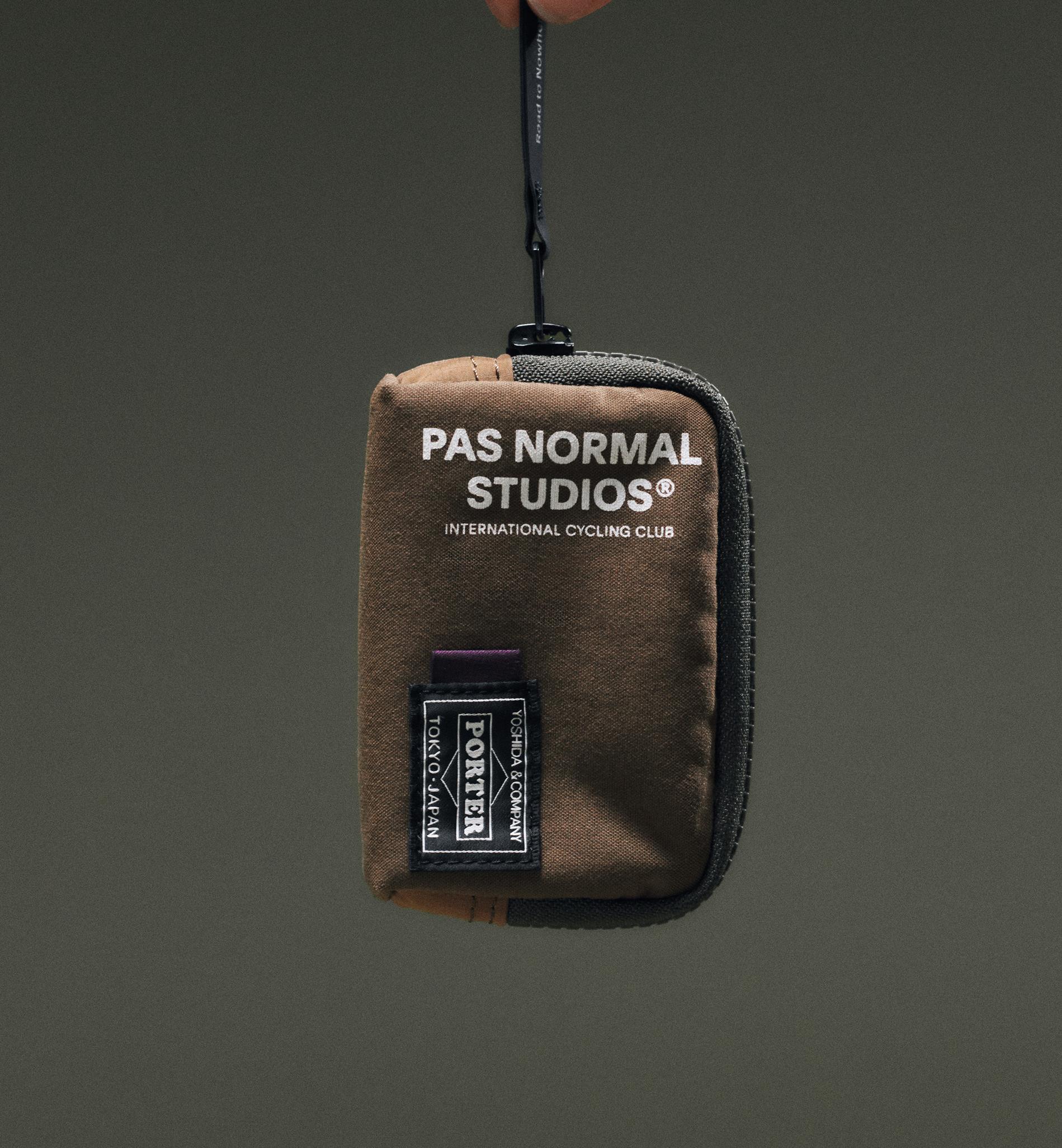 Light Brown Porter-Yoshida coin case held by hand, front view with white logo print and Porter woven patch