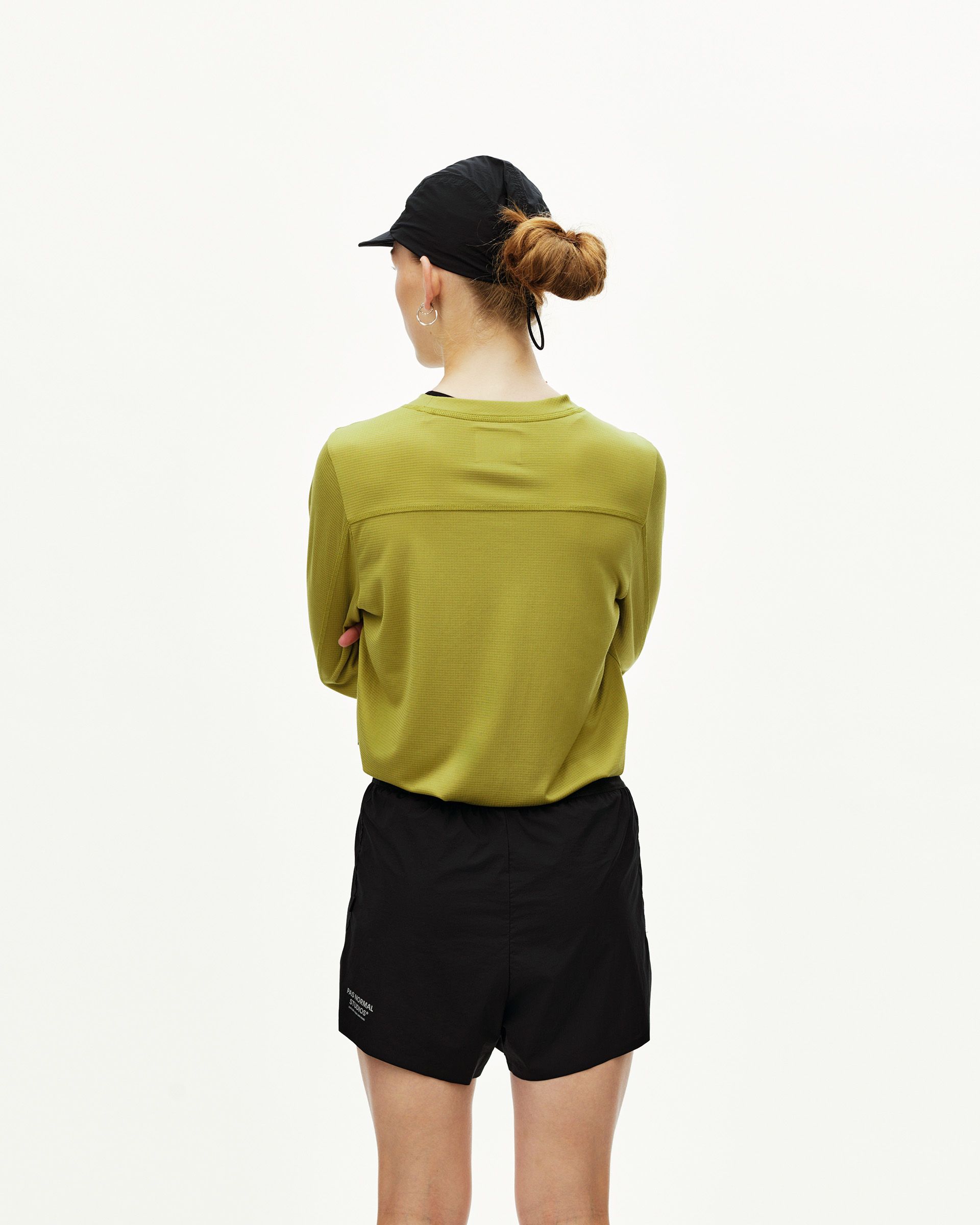 Black Balance 2-in-1 Shorts on model, rear view with olive long-sleeve top