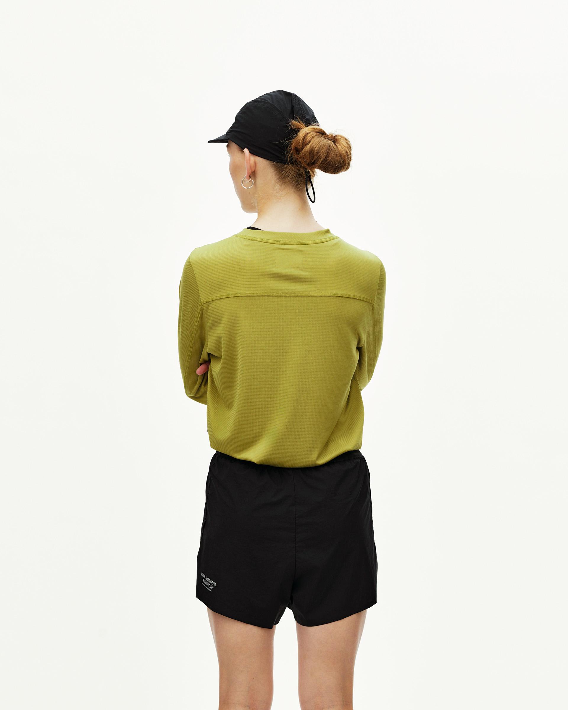 Black Balance 2-in-1 Shorts on model, rear view with olive long-sleeve top