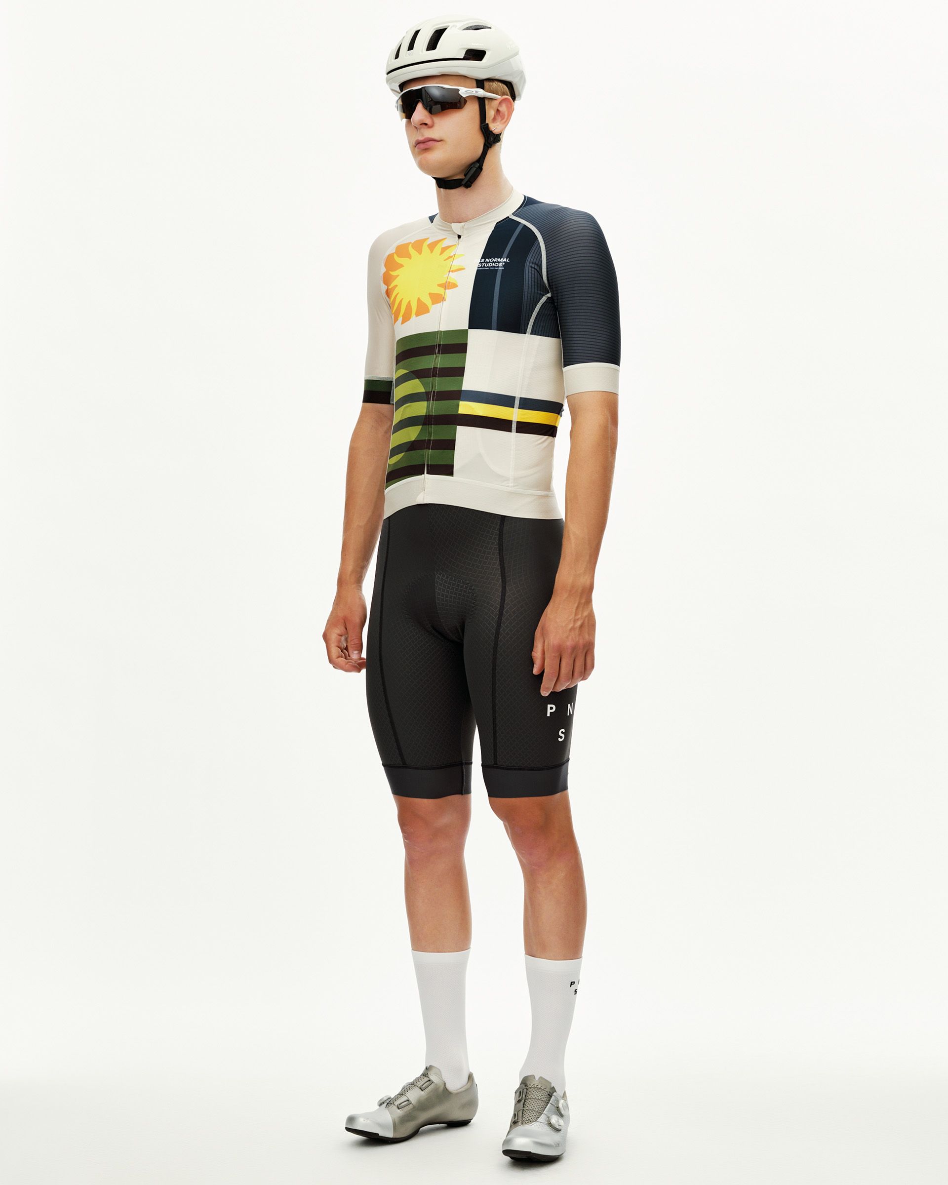 International Sand Mechanism men's cycling jersey on model, front three-quarter view with bold graphic sun and stripe print
