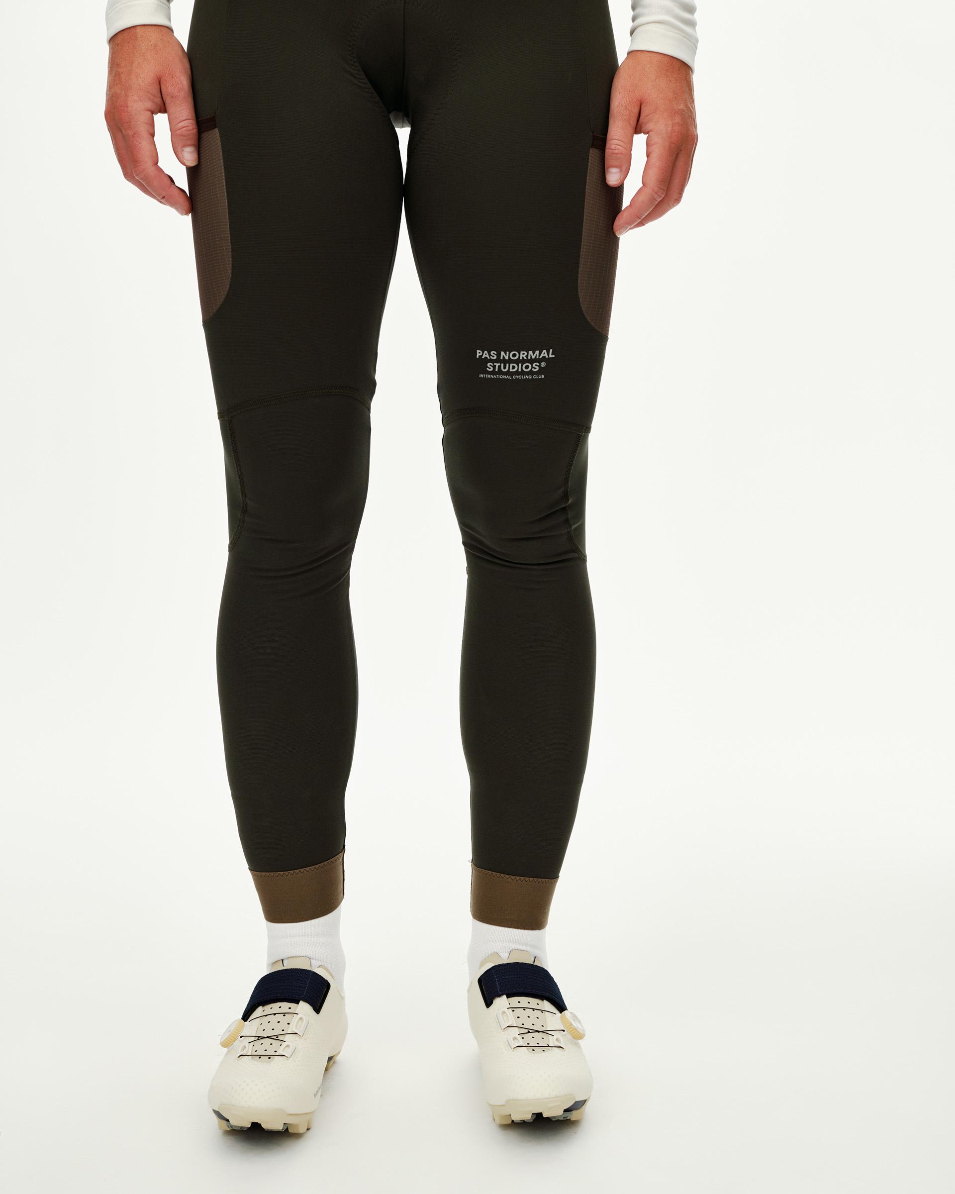 Dark Olive Escapism Long Cargo cycling bibs on model, front view with contrast panel and ribbed ankle cuff