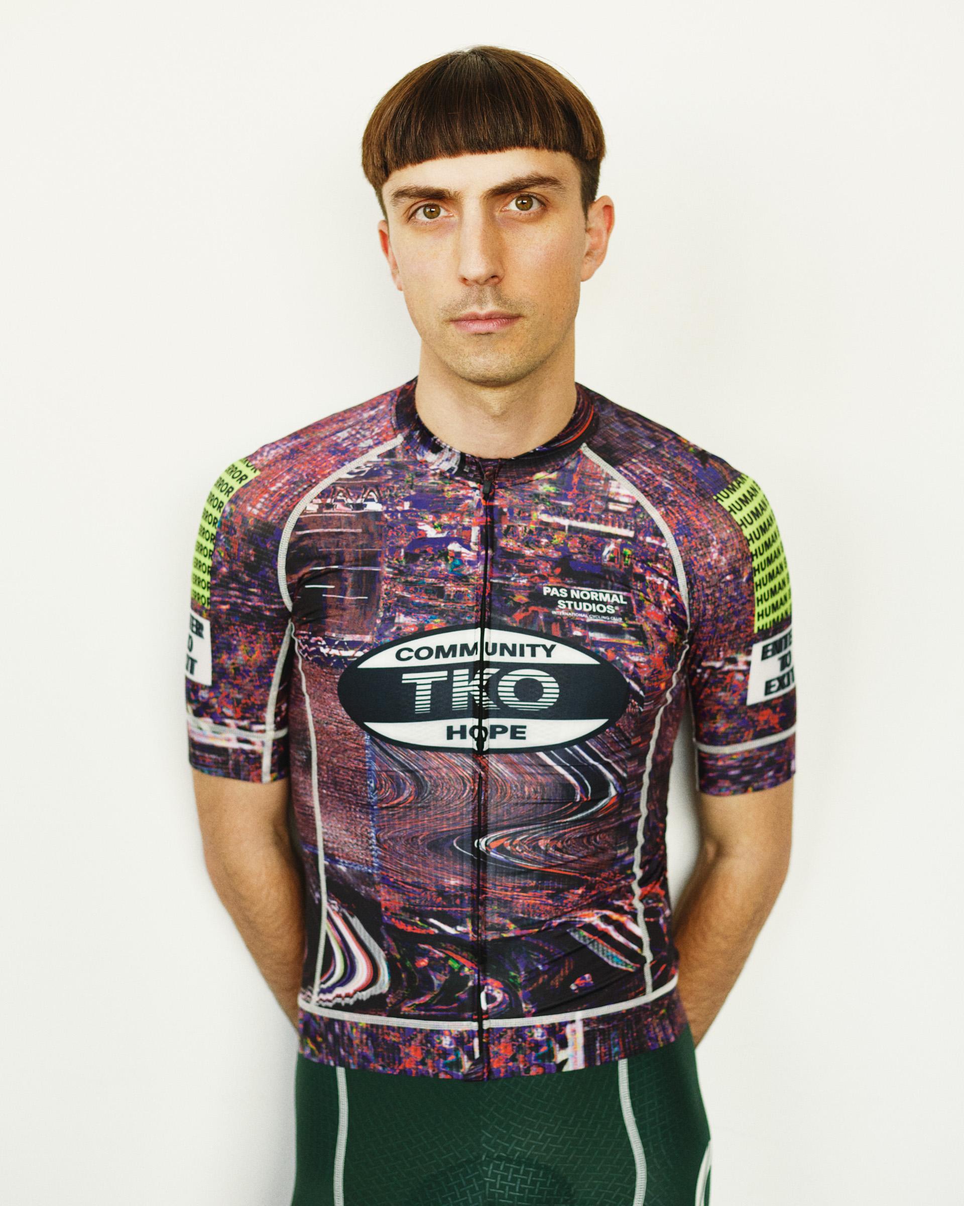 Human Error Pink T.K.O. Mechanism cycling jersey on model, front view with glitch cityscape AOP and neon sleeve print