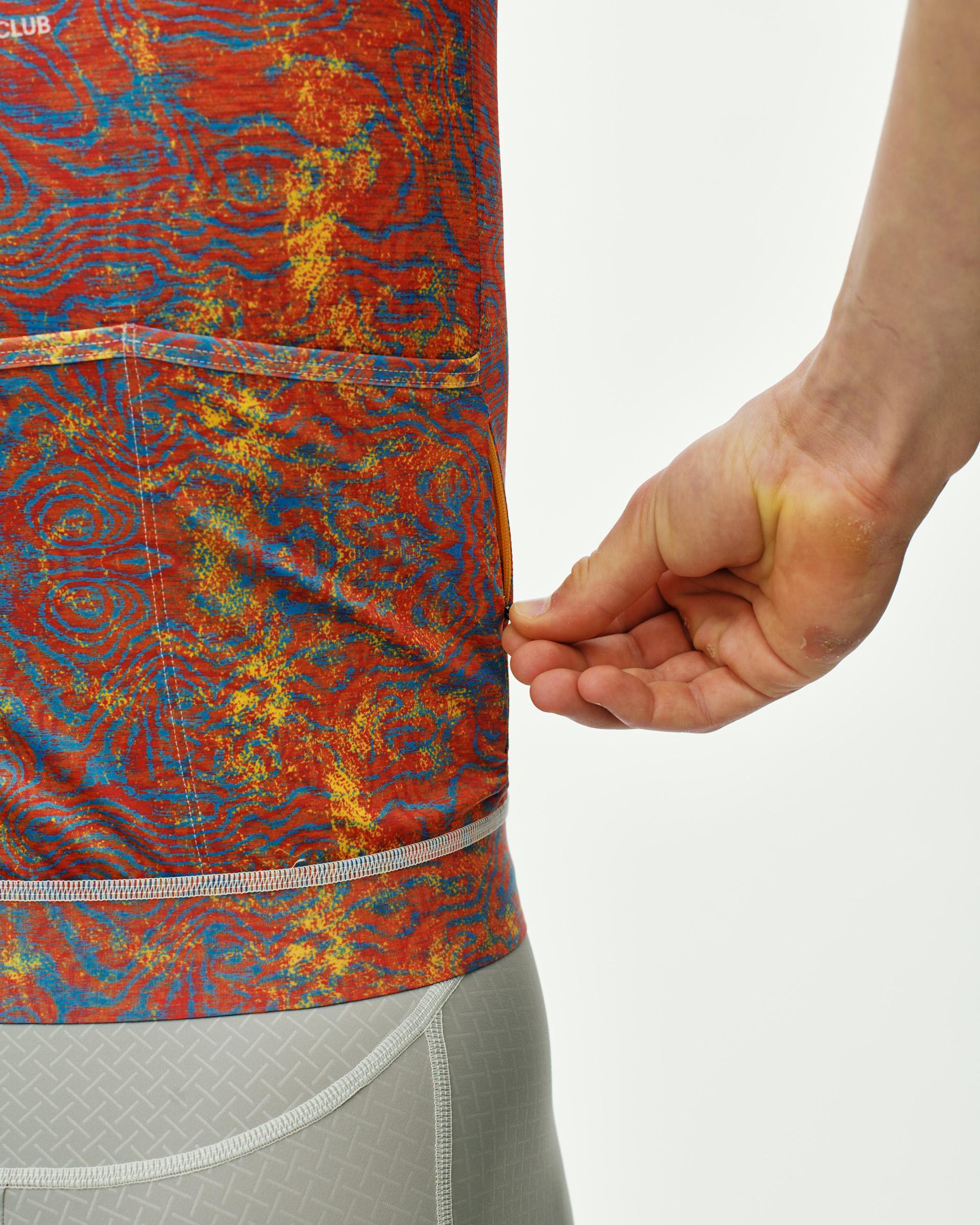 Breakfast Club Mechanism cycling jersey, side detail on model showing rear pocket and zip hem — multicolor swirl print