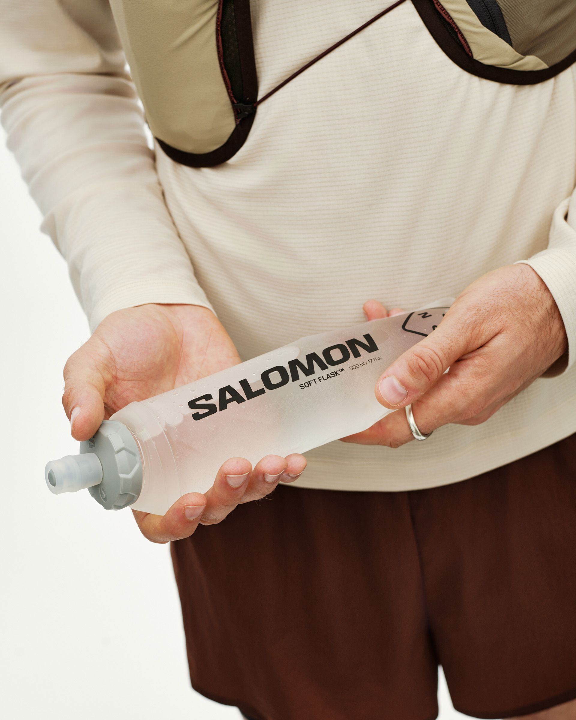 Light Brown Salomon Gravel Concept Skin 2 soft flask held in hands on model, front detail view with grey nozzle cap