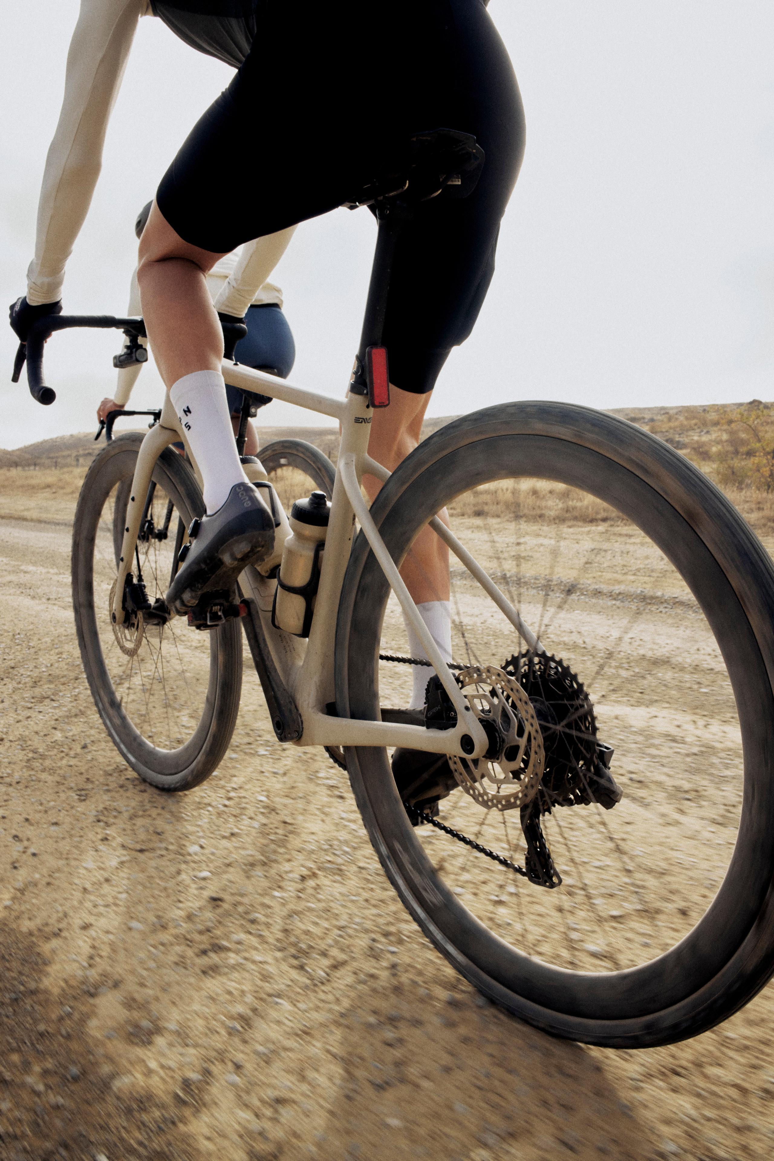 Model wearing black cycling shorts on time trial bike in desert landscape