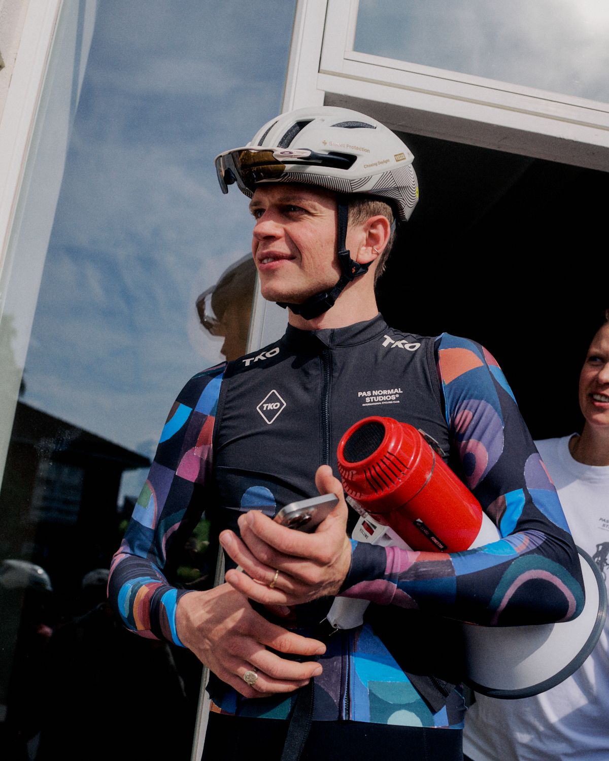 Model wearing men's cycling jersey with geometric blue and purple pattern holding trophy