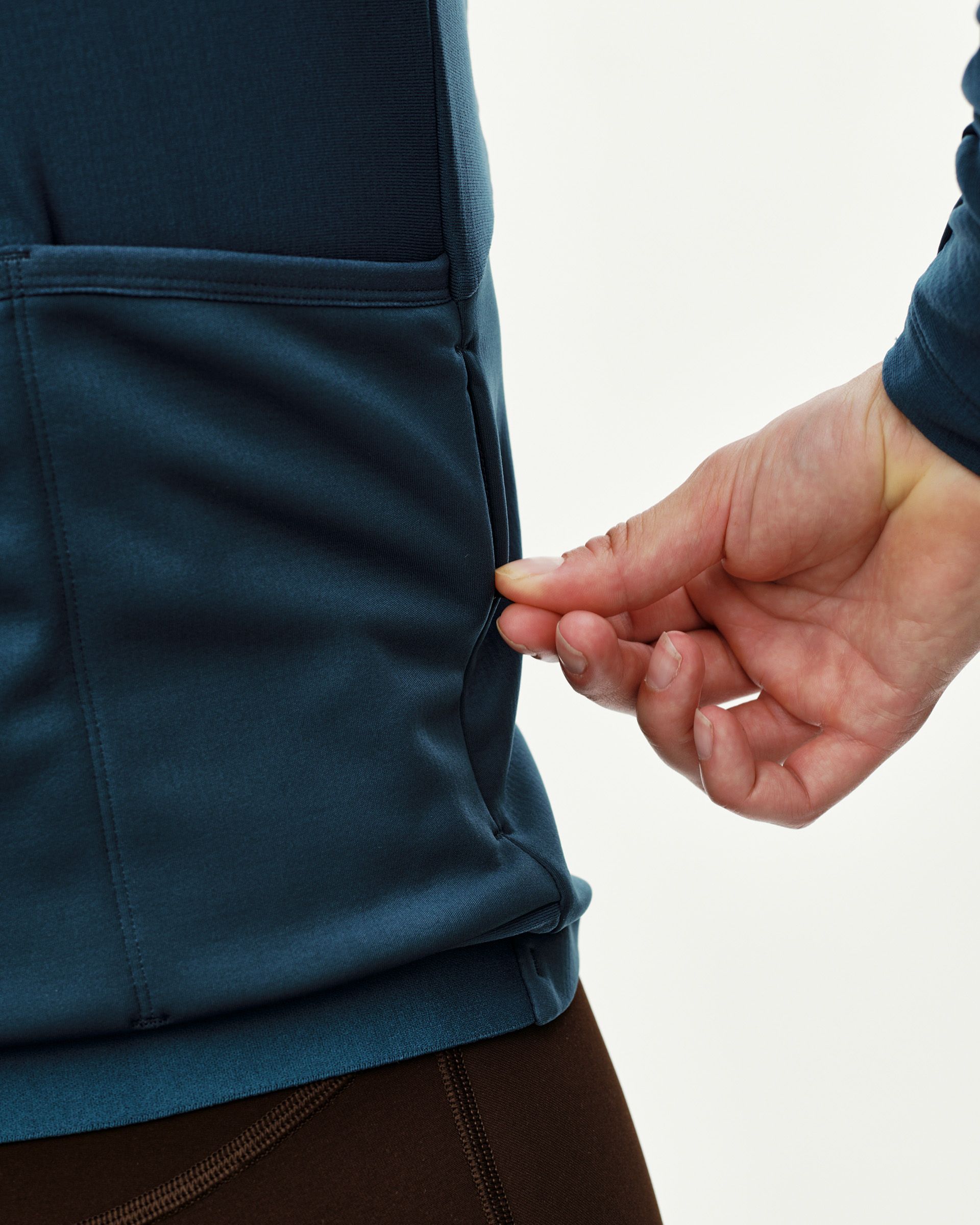 Denim Blue Mechanism Thermal Long Sleeve cycling jersey, side detail on model showing rear pocket opening