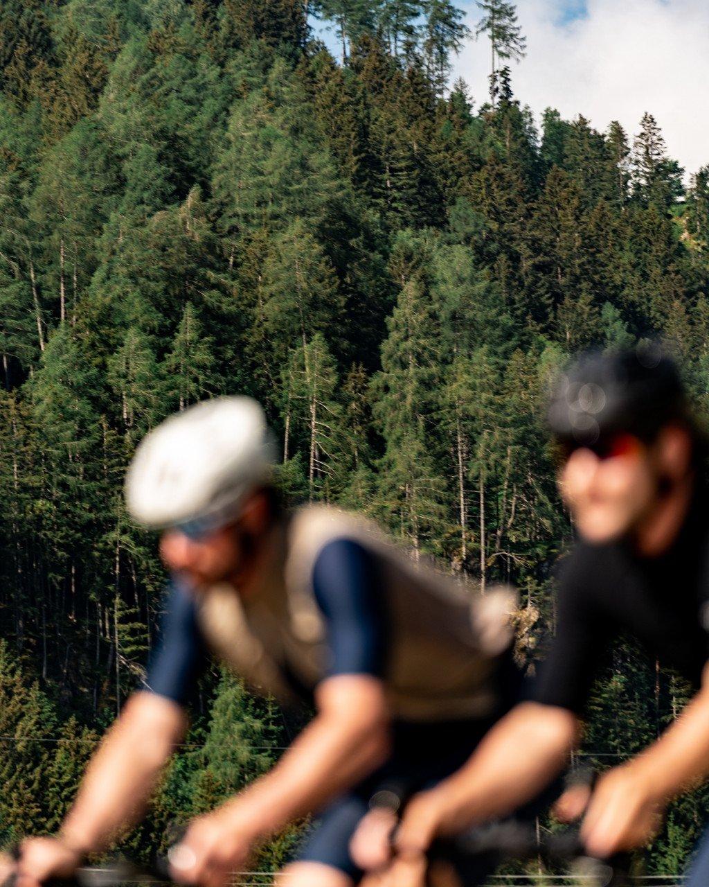 Blurred cyclists in motion through forested landscape