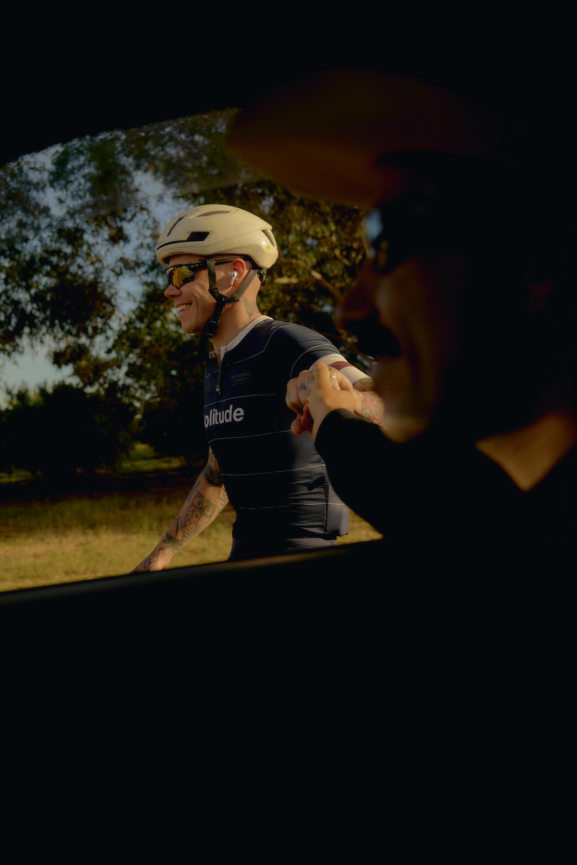 Model wearing black Solitude jersey with white helmet during golden hour training session