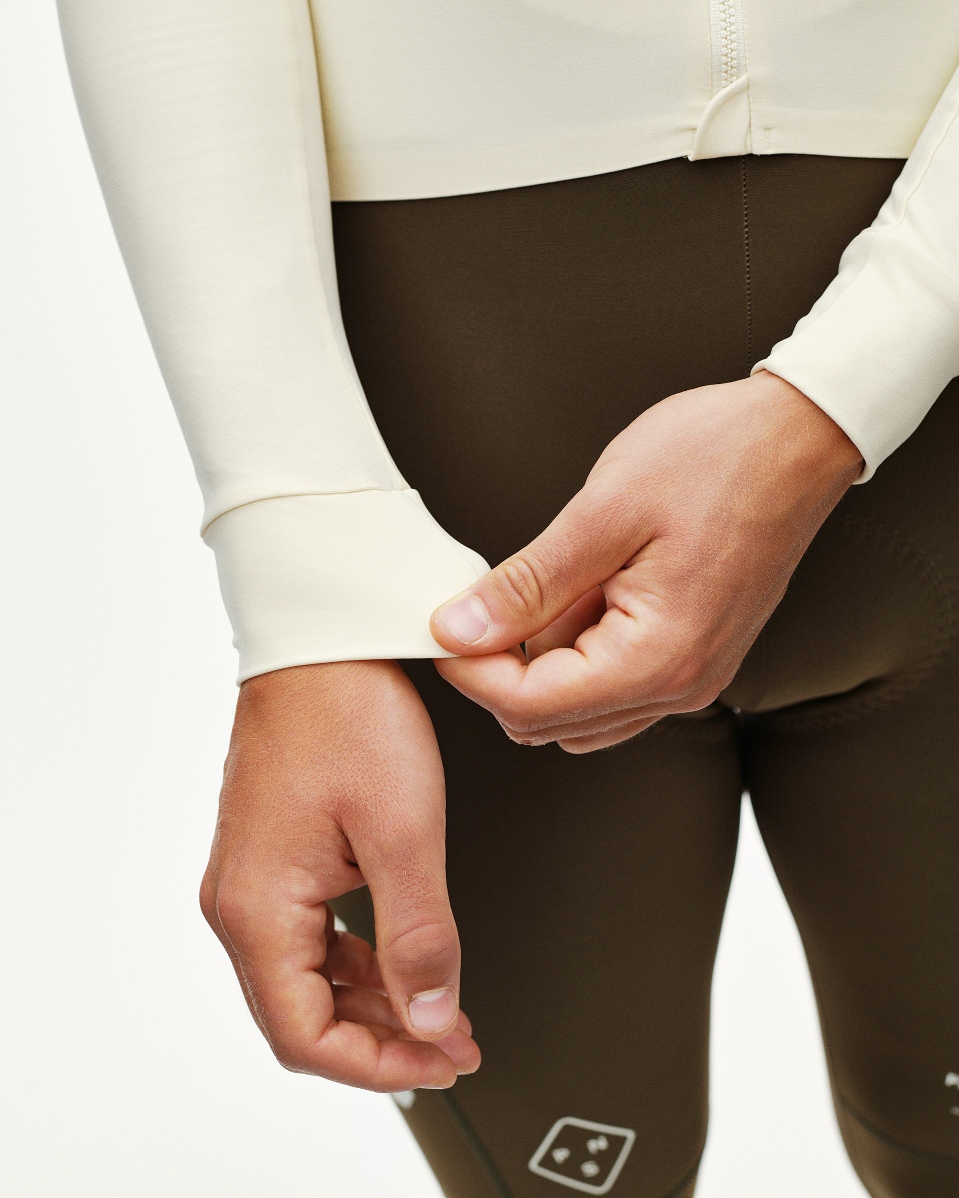 Sand PAS Mechanism long sleeve cycling jersey, detail view on model showing ribbed cuff with dark olive bib tights