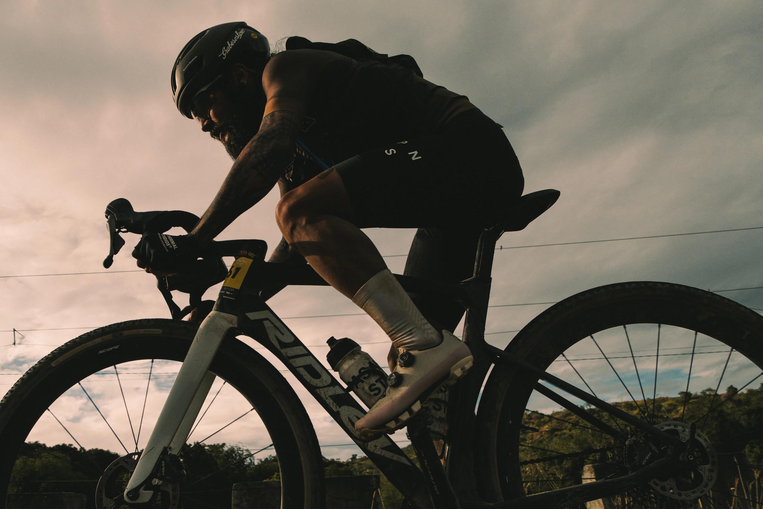 Cyclist in aerodynamic position on time trial bike during golden hour in Philippines countryside