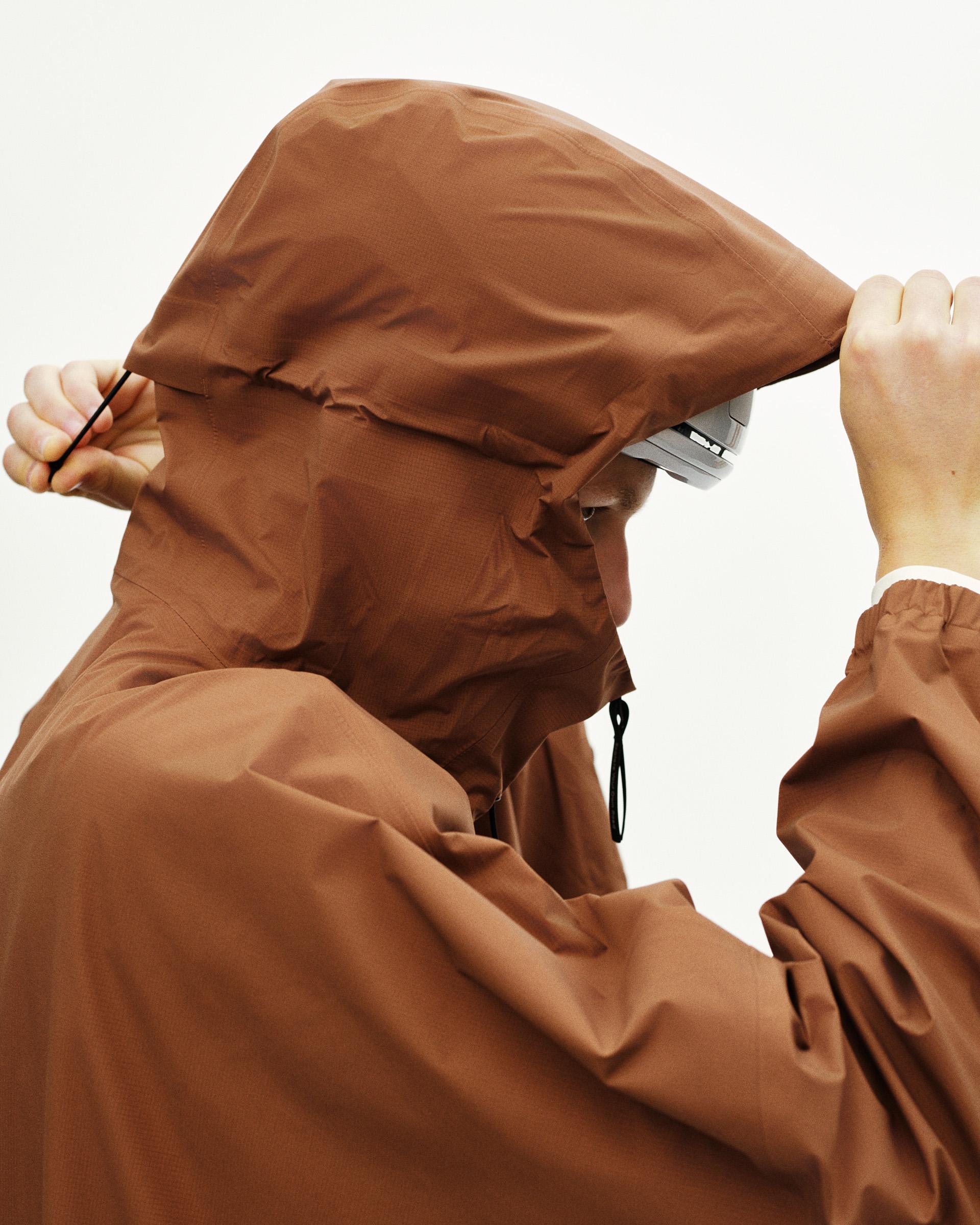 Brown Off-Race 3L Poncho on model pulling hood up over head