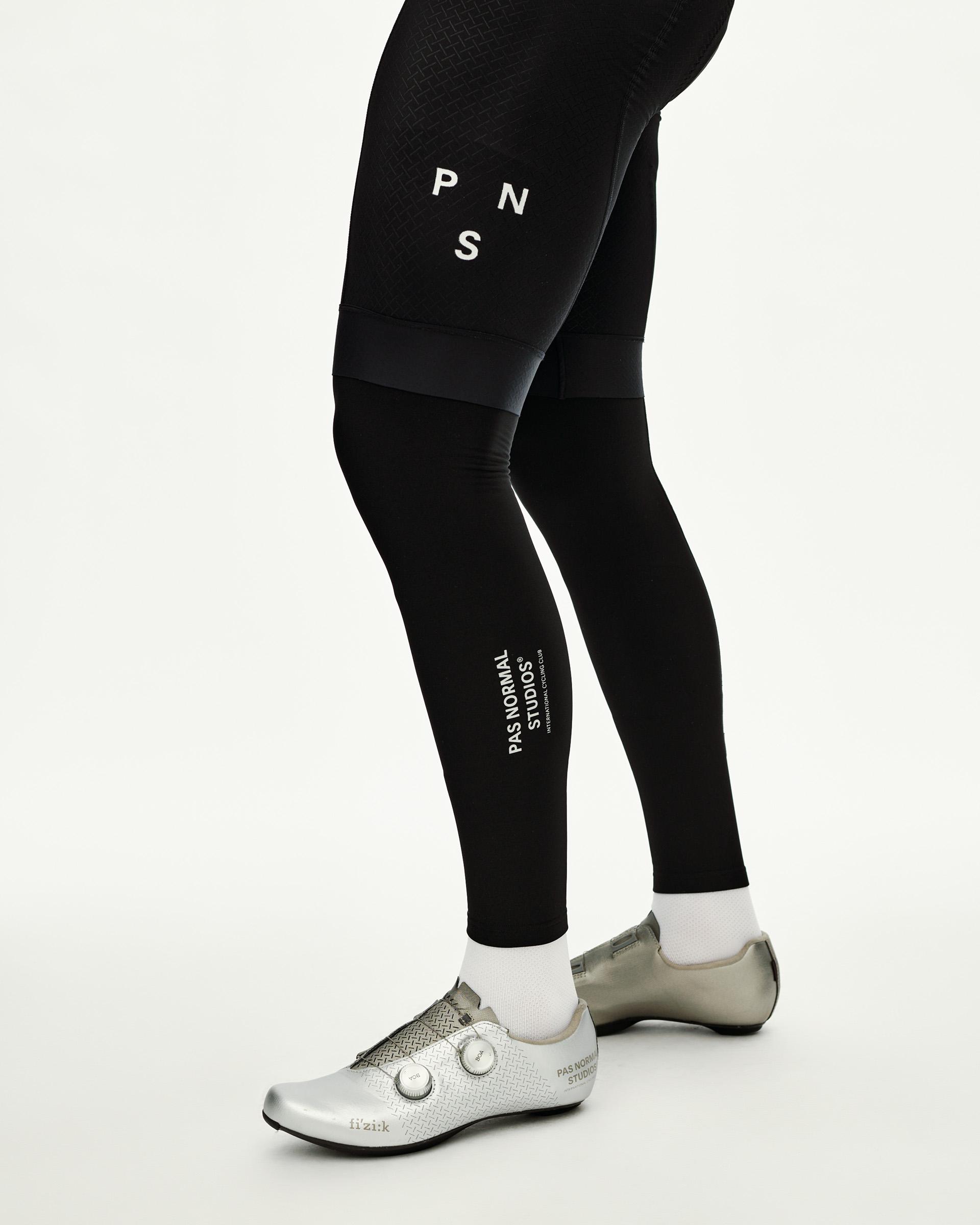 Black Logo cycling leg warmers on model, side view with white stacked logo print