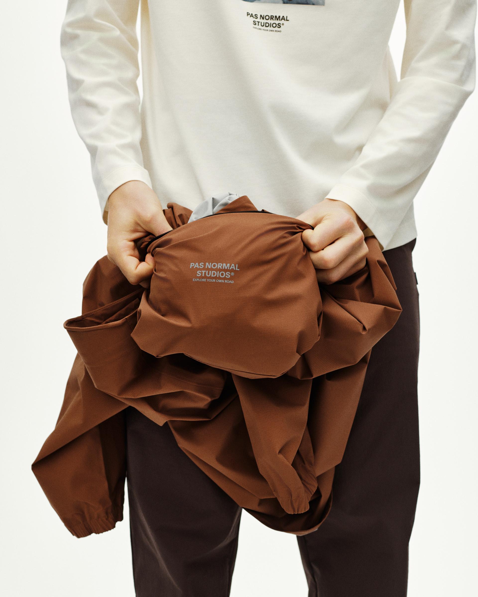 Brown Off-Race 3L Poncho outerwear held by model showing packable design
