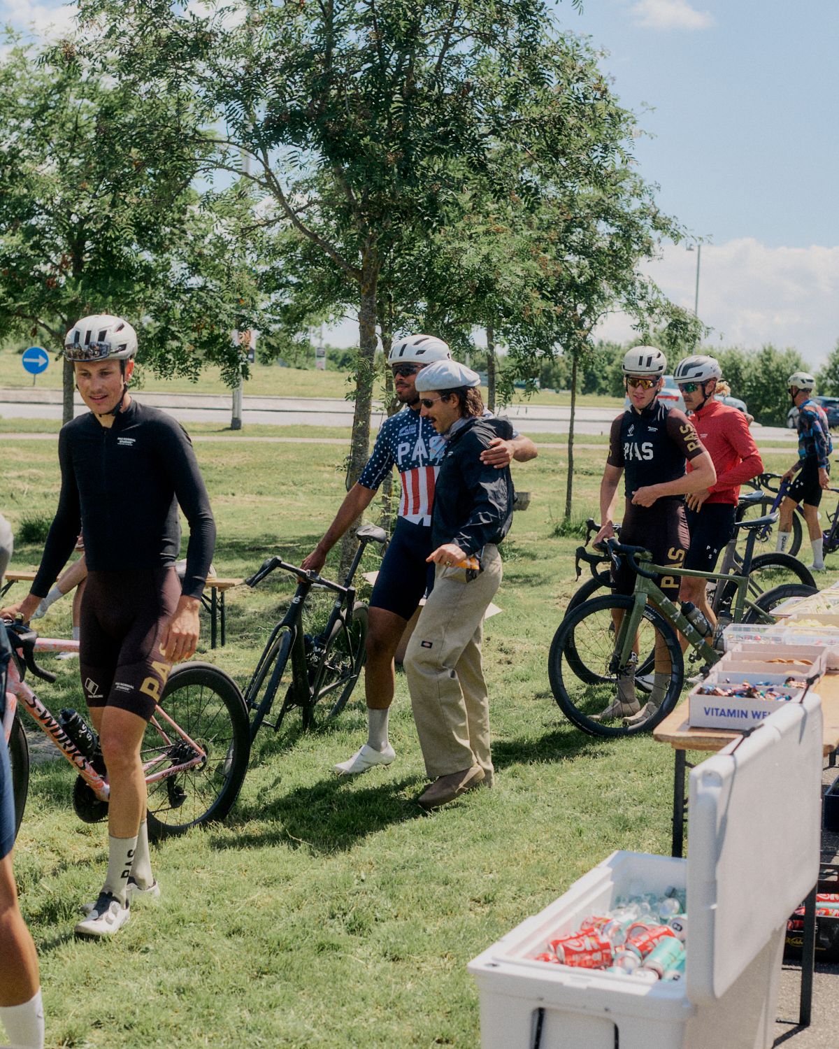 Cyclists at outdoor event with bikes and refreshment station in park setting