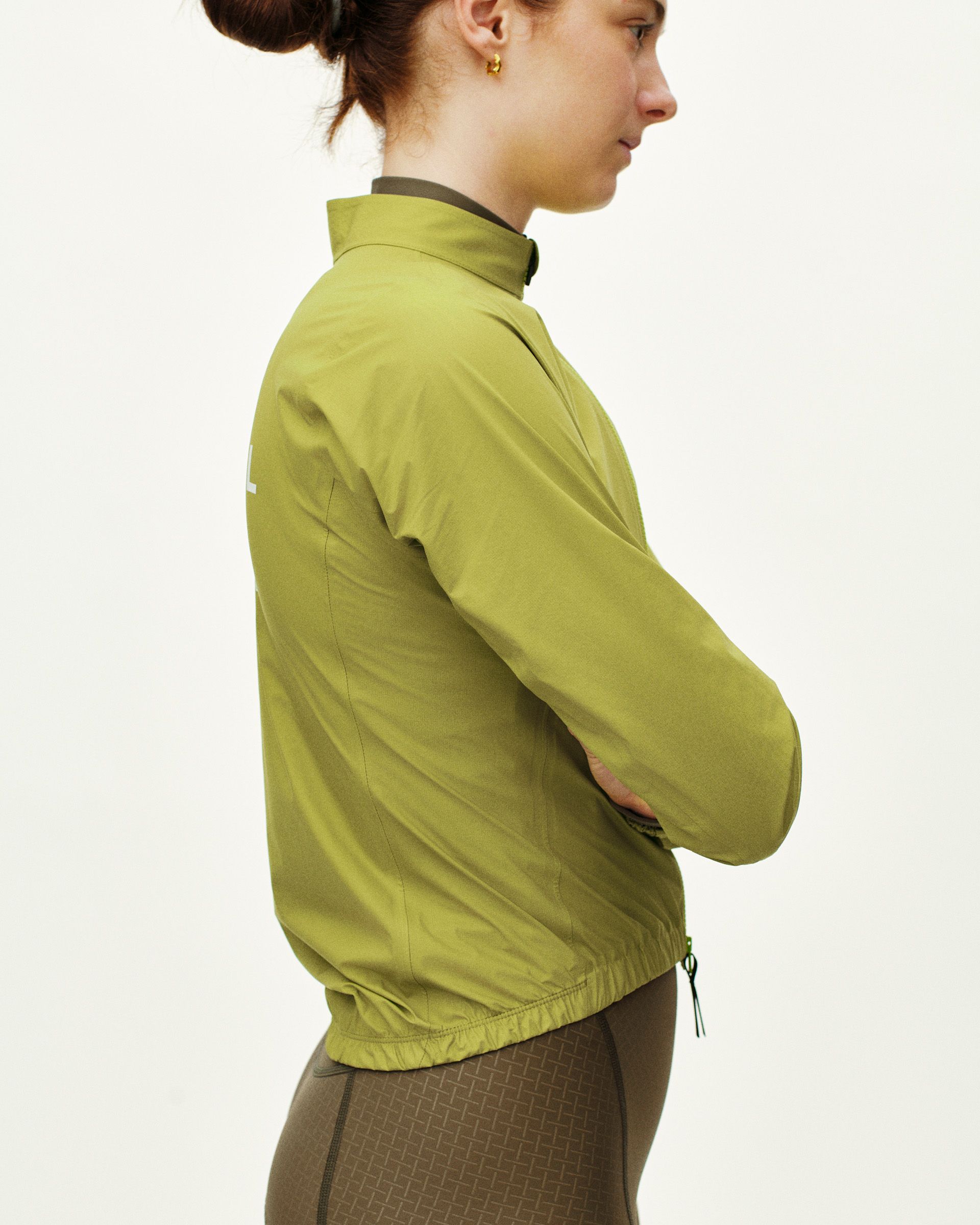 Green Mechanism Rain cycling jacket on model, side view with elastic hem and drawcord