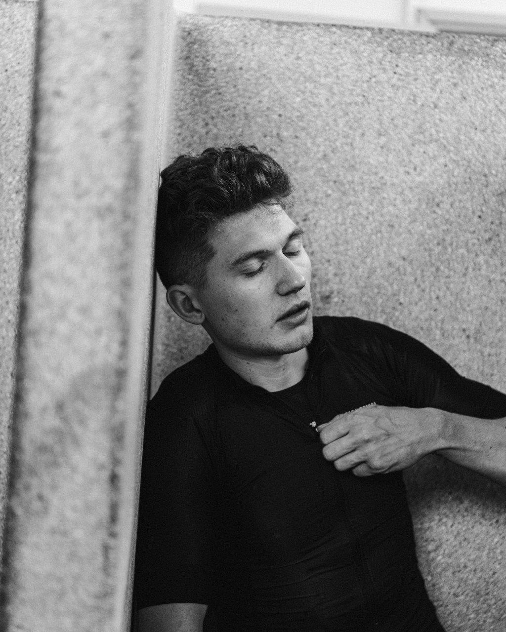 Model wearing black t-shirt against concrete wall in black and white portrait