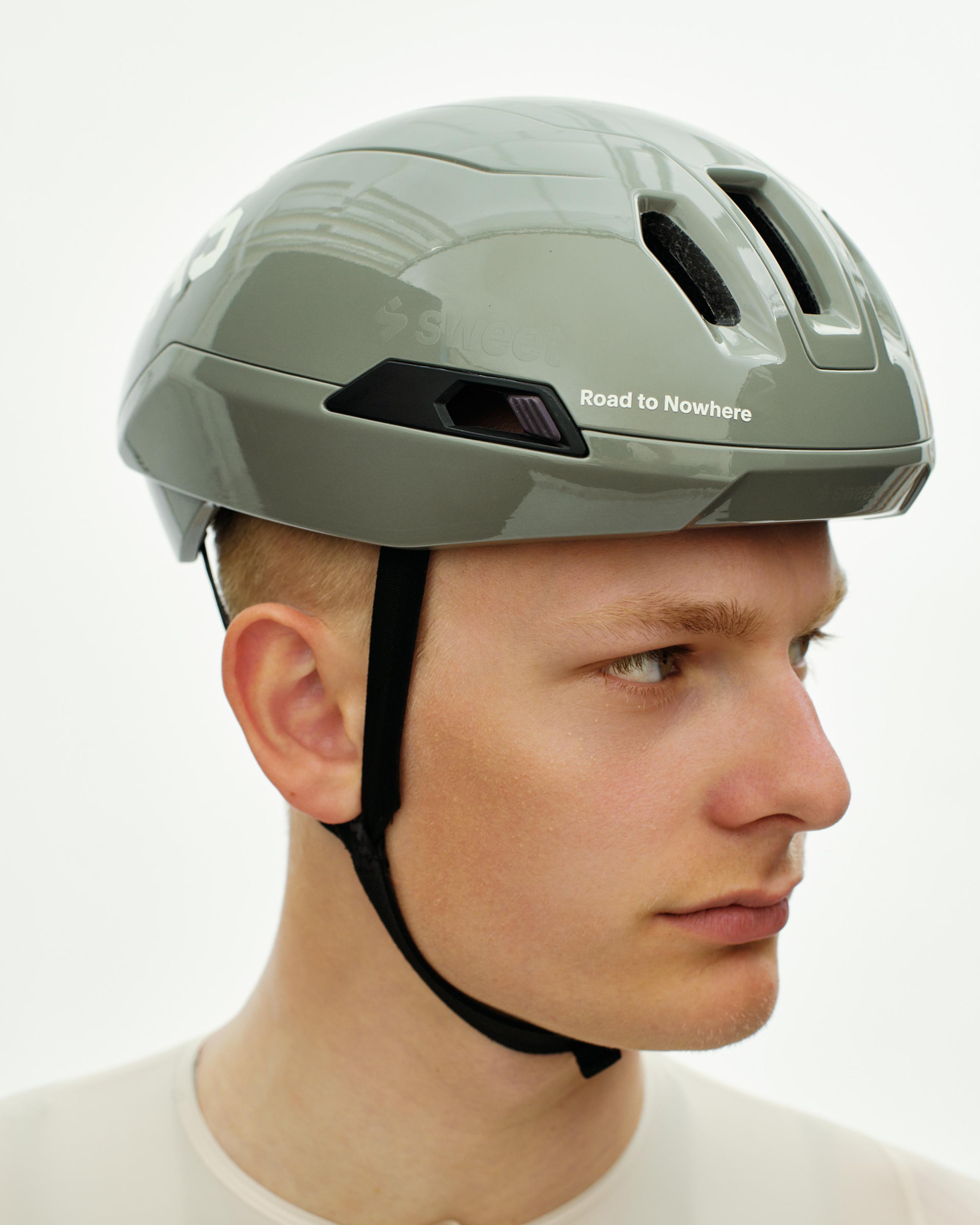 Grey PAS Tucker III 2Vi MIPS cycling helmet on model, side view with Road to Nowhere branding