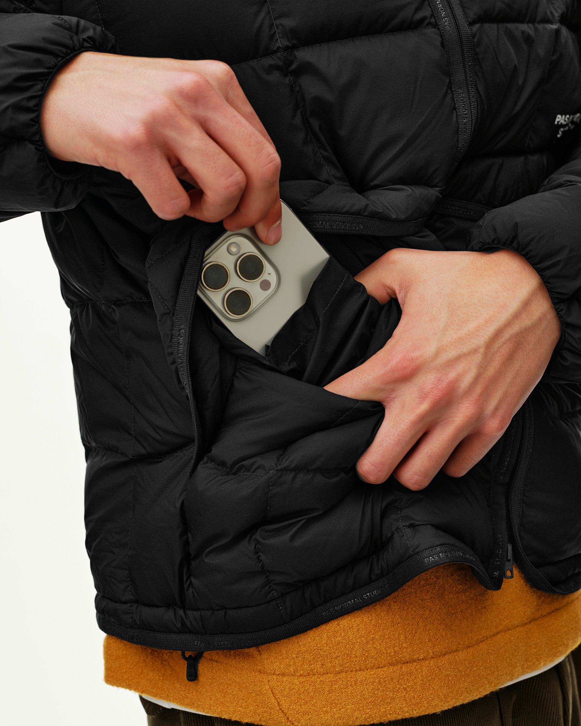 Black Off-Race Down Liner jacket, detail view of zip pocket with phone being inserted on model