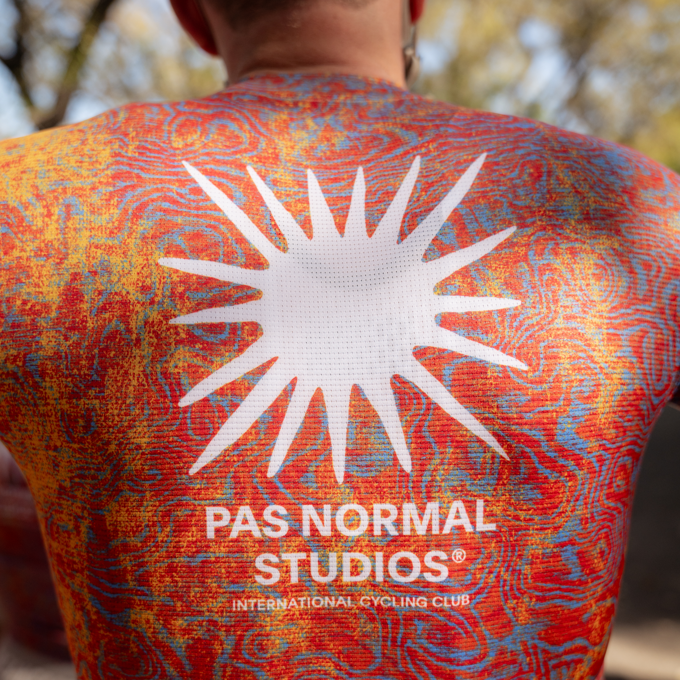 Model wearing multicolor swirl print jersey with white sun graphic on back