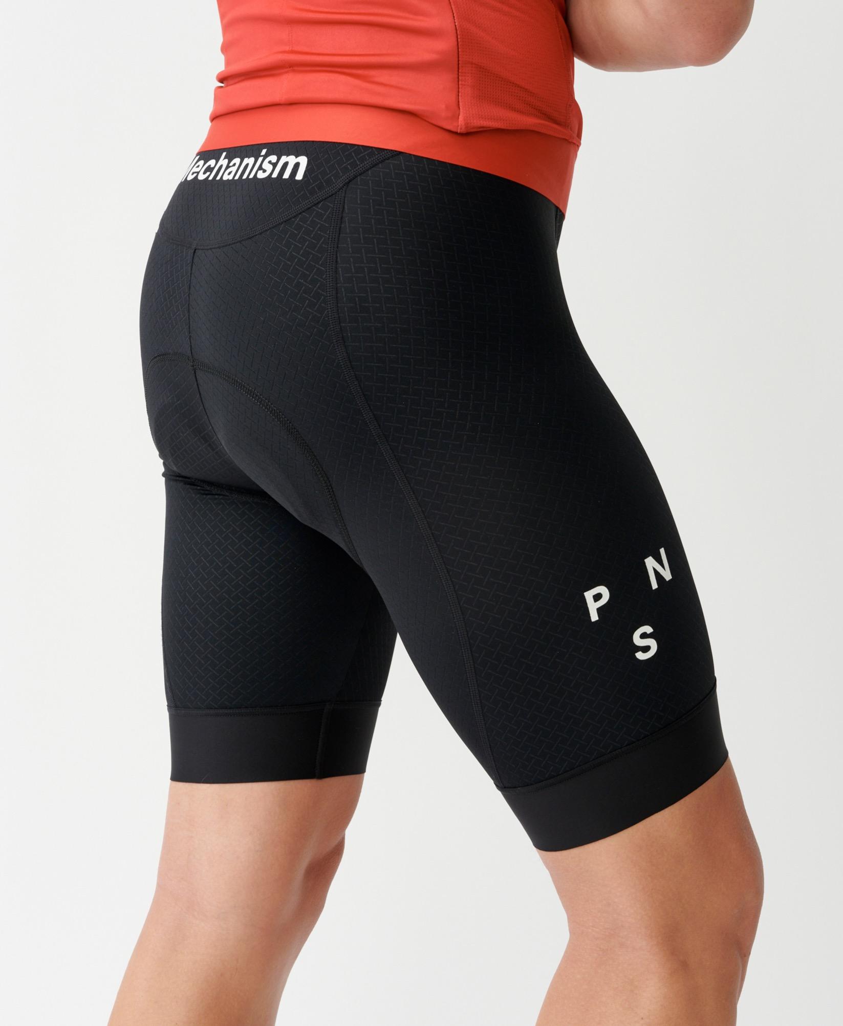 Black Mechanism cycling bibs on model, side view with textured fabric panels and white leg branding