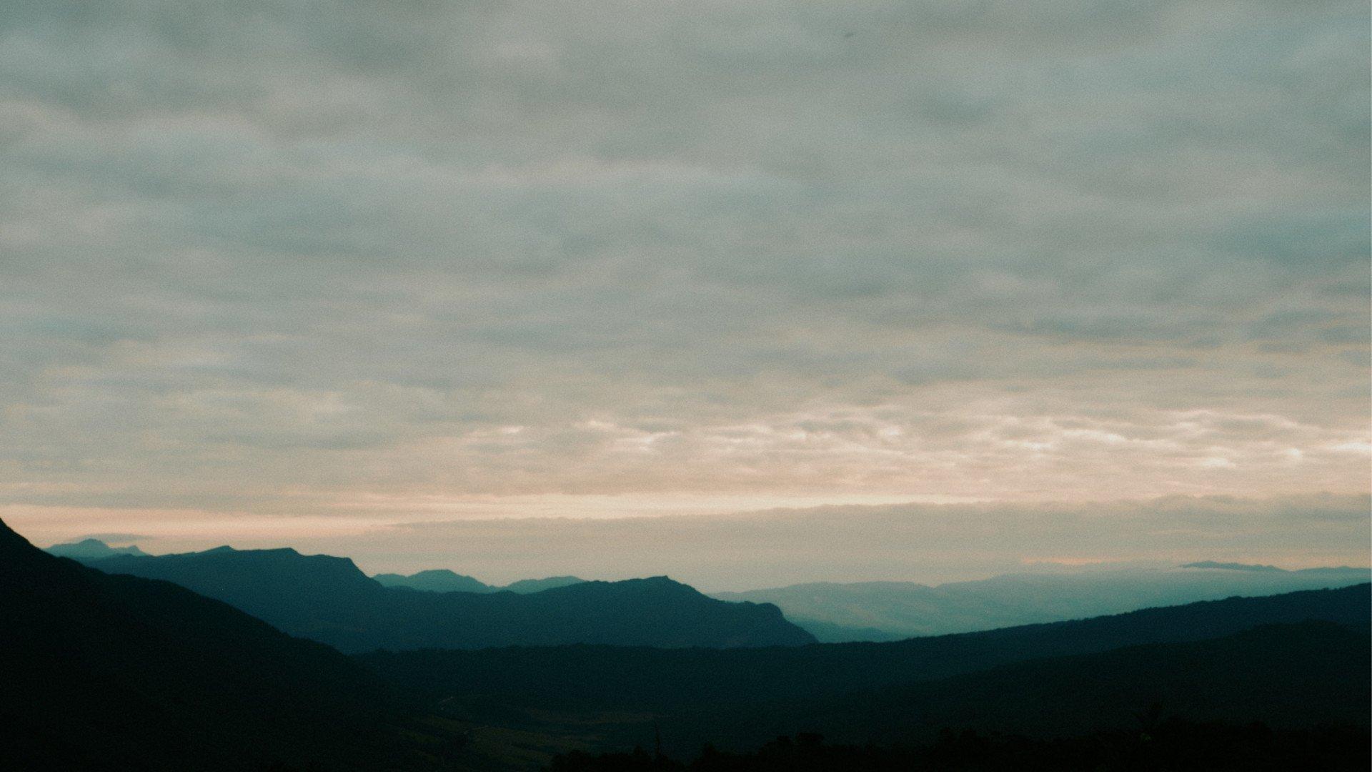 Mountain landscape with layered peaks under cloudy sky at dawn or dusk