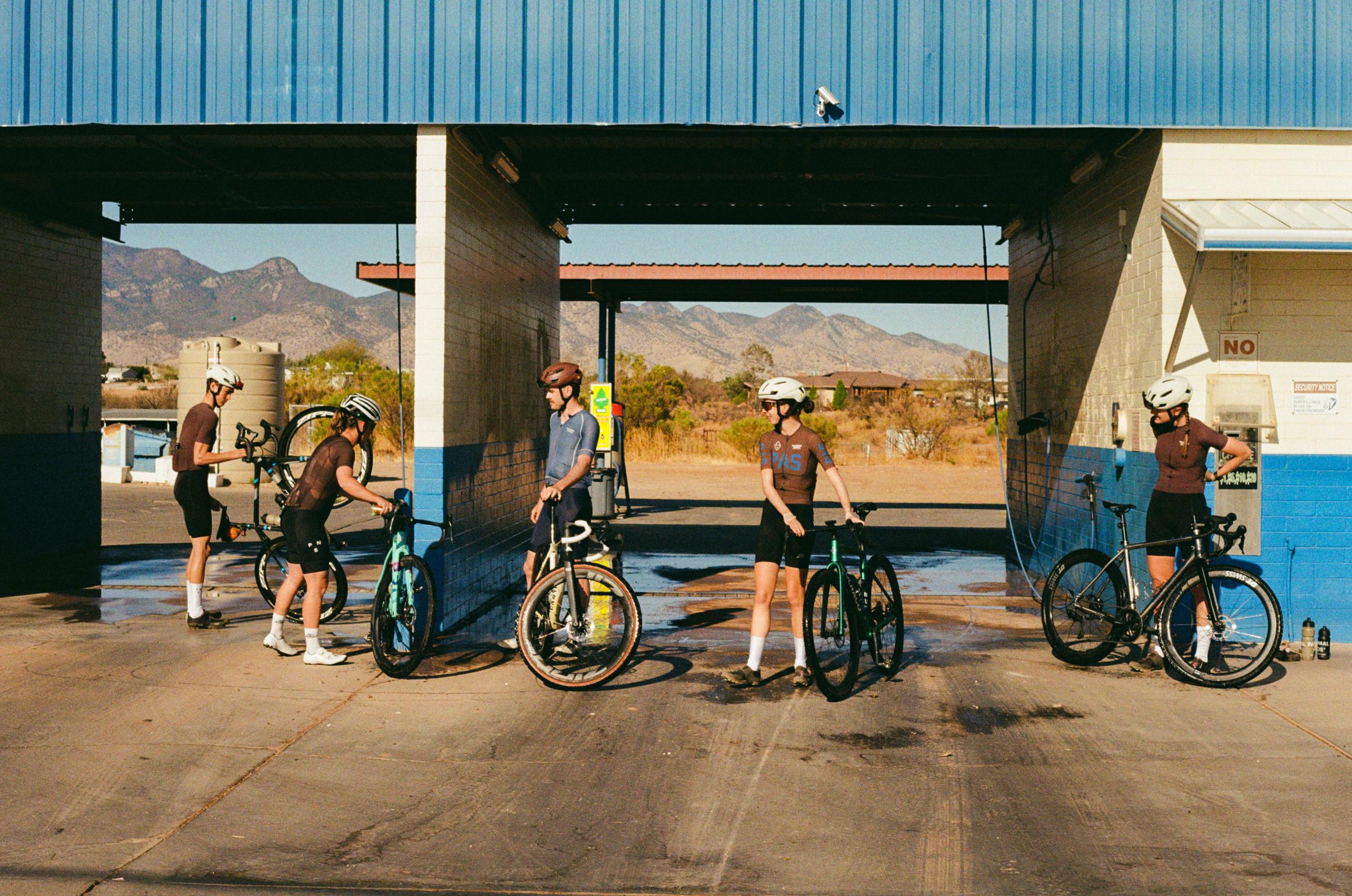 Cyclists at gas station with bikes during desert training ride in mountainous landscape