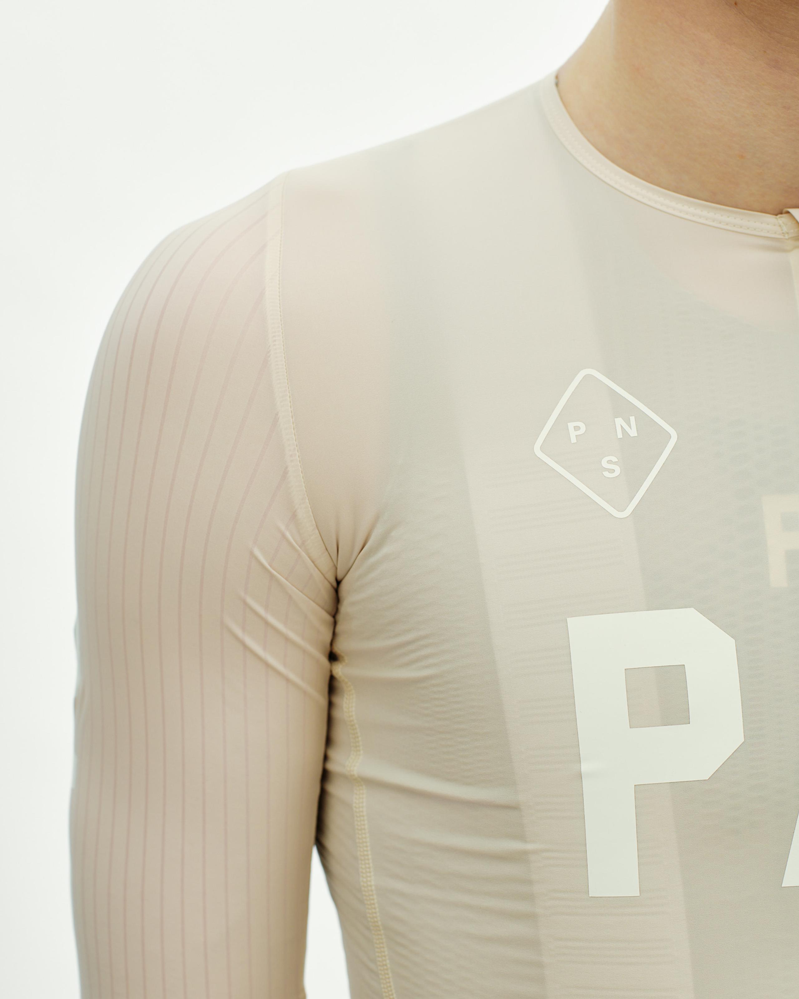 Cream PAS Mechanism Pro cycling jersey on model with white chest logo and ribbed sleeves